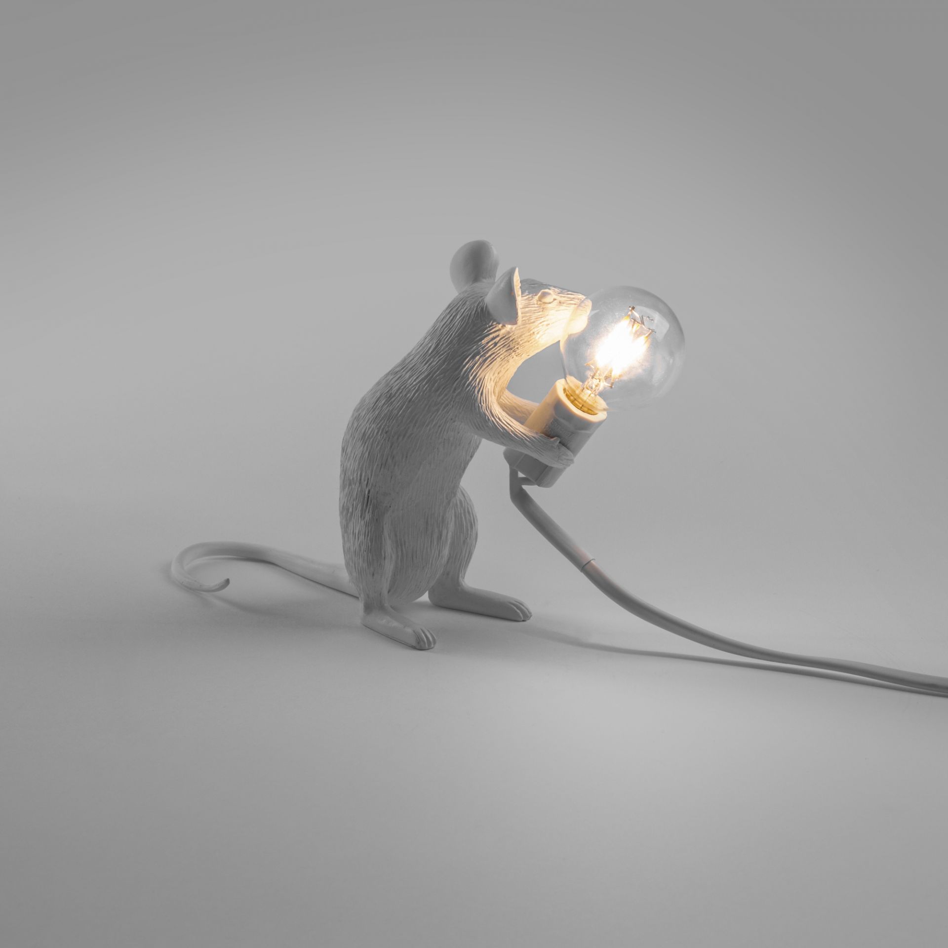 Weiße Seletti Mouse Lamp Tischleuchte sitzend mit USB Kabel und leuchtender Glühbirne.
