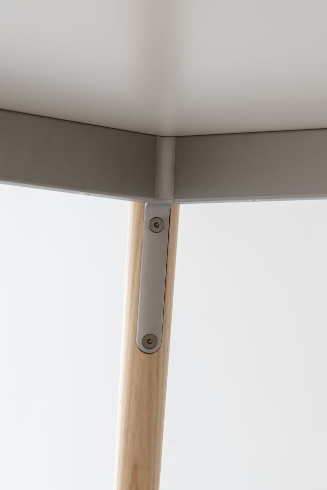 Detailaufnahme des Pilo Tischbeins von Magis: Holzbein mit Metallbefestigung am grauen Tisch.