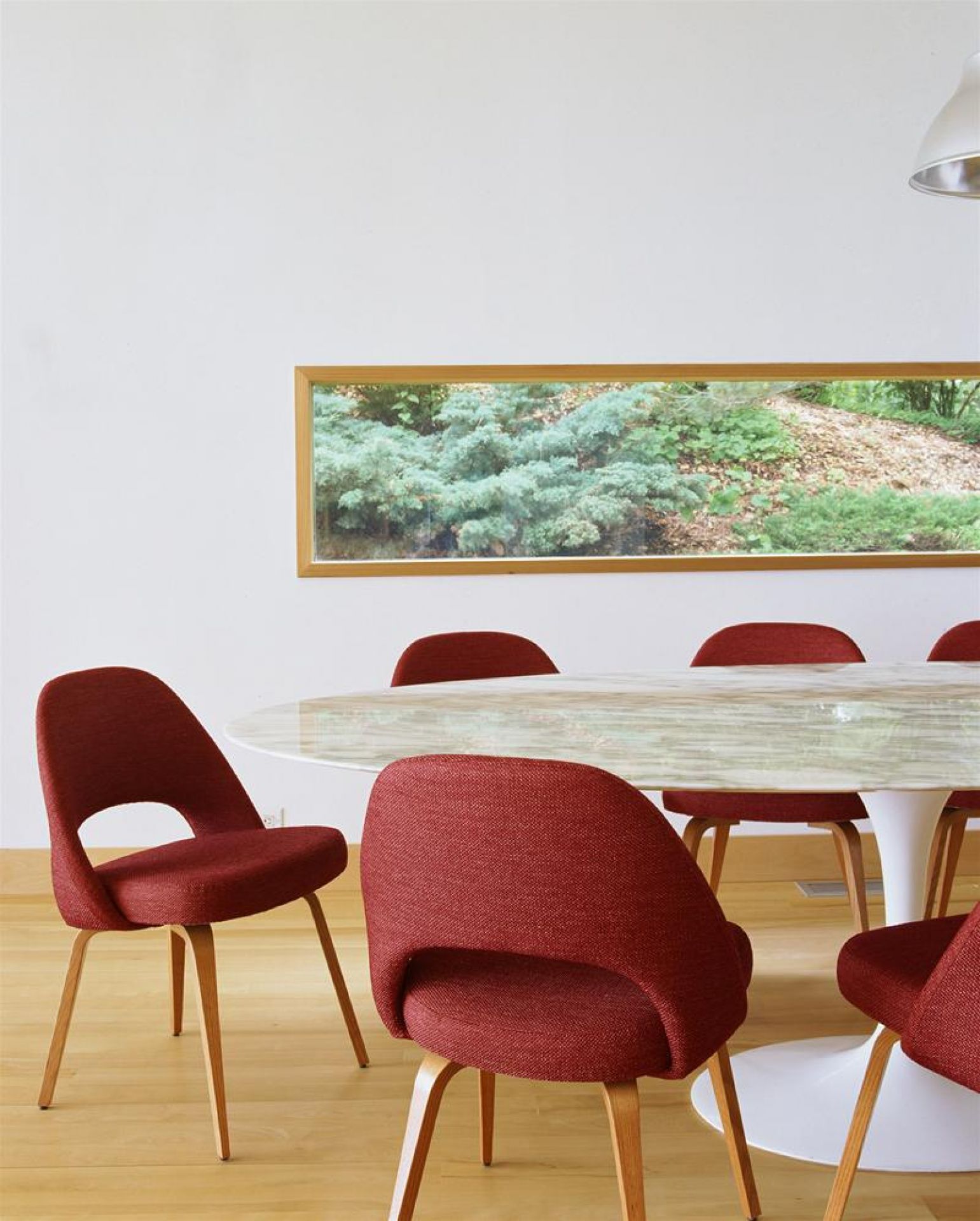 Weißes Saarinen Esstisch Untergestell von Knoll International mit runder Tischplatte und roten Stühlen in einem Esszimmer.