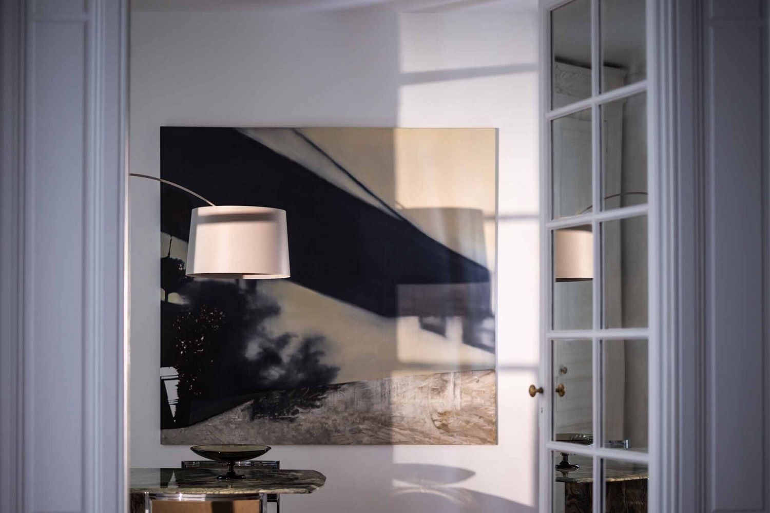 Elegante Twiggy Stehleuchte von Foscarini mit beigem Lampenschirm in stilvollem Ambiente mit Kunstwerk und Glastür.