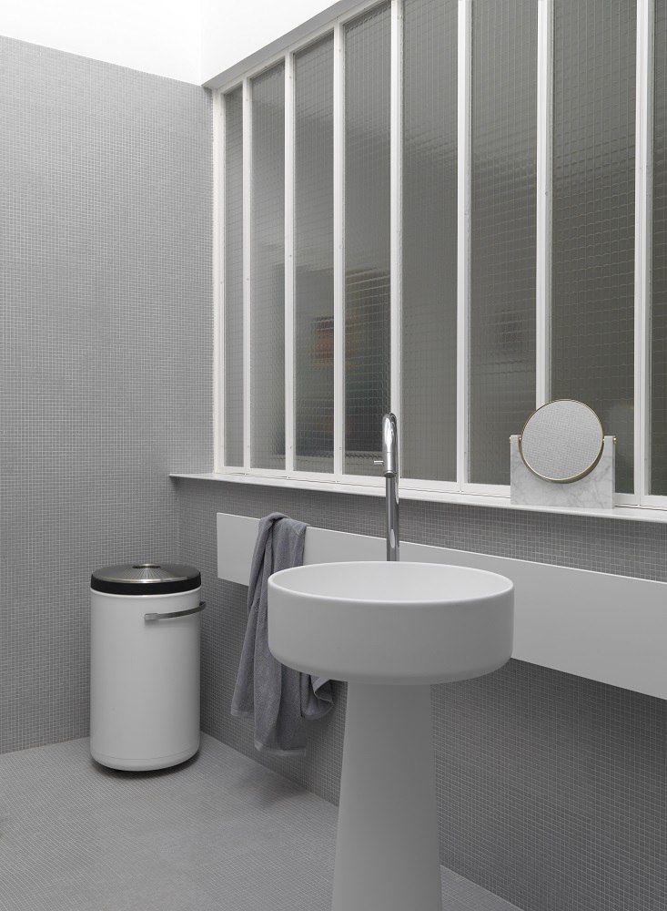 Weißer Vipp Wäschekorb im modernen Badezimmer mit Waschbecken, Spiegel und Fenster für stilvolle Badgestaltung.