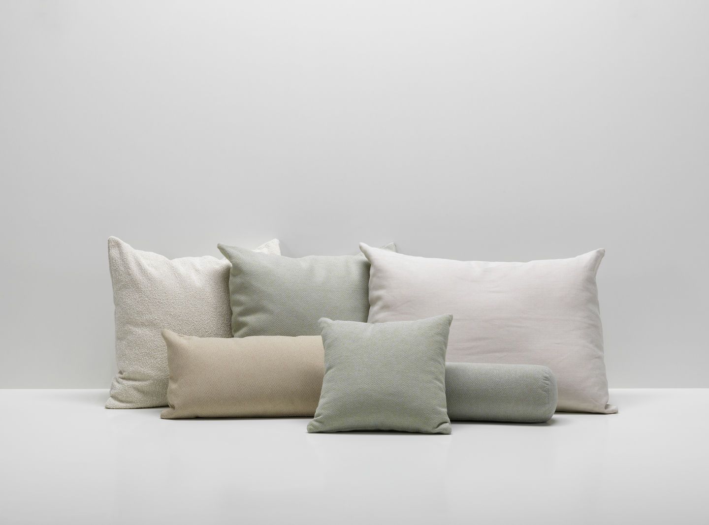 Vitra Kissen-Kollektion: Verschiedene Sofakissen in Weiß-, Beige- und Grüntönen auf weißem Hintergrund. Dekorative Wohnaccessoires für Sofa und Wohnbereich.