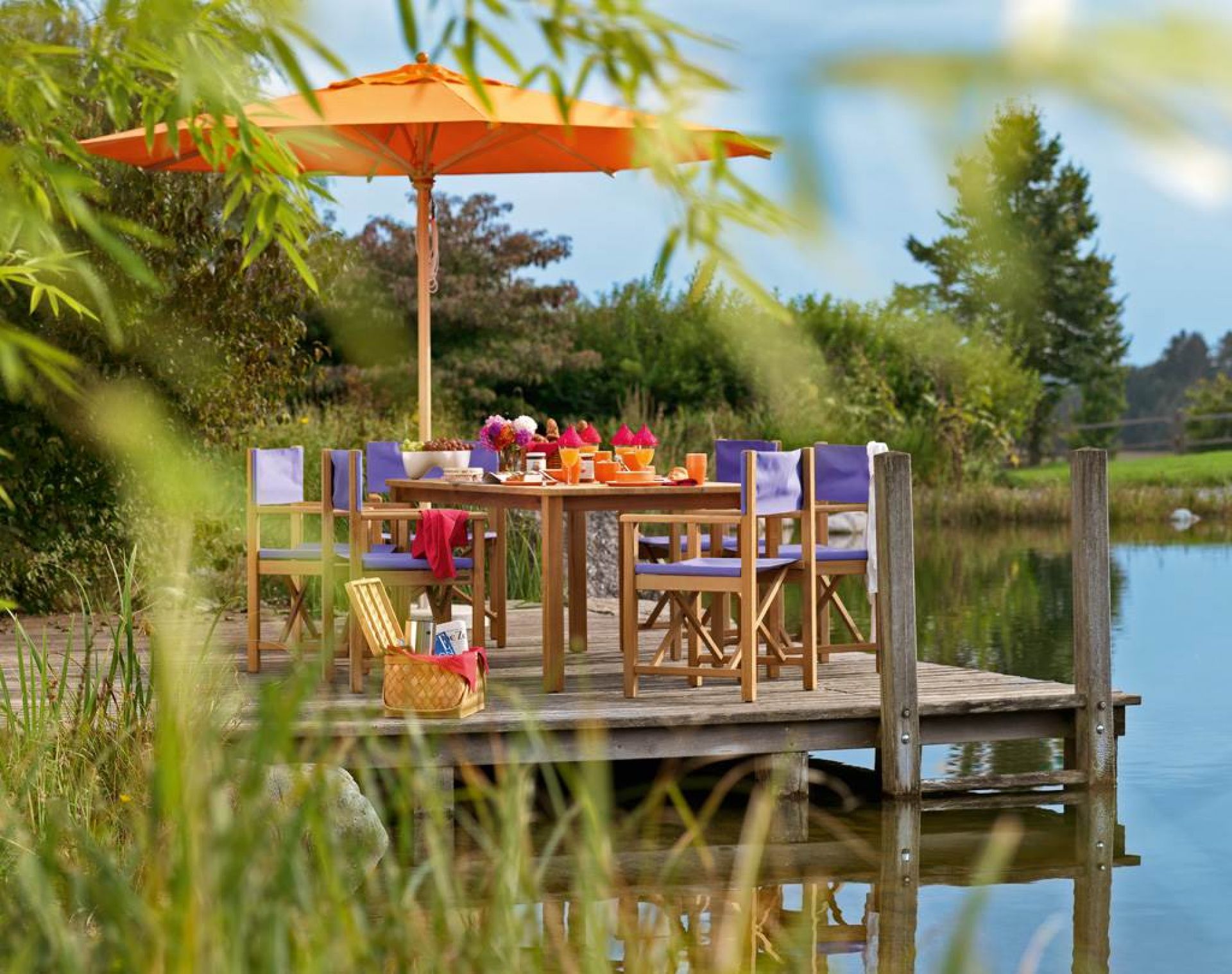Weishäupl Cabin Sessel in Kirschrot auf Holzsteg am See, Teil einer Gartenmöbel-Gruppe.