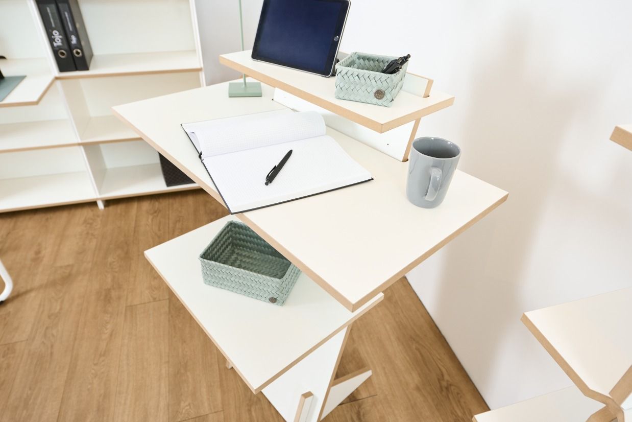 Tojo Pult Stehpult aus Holz, höhenverstellbar, mit Notizbuch, Stift, Tablet und Kaffeetasse dekoriert.