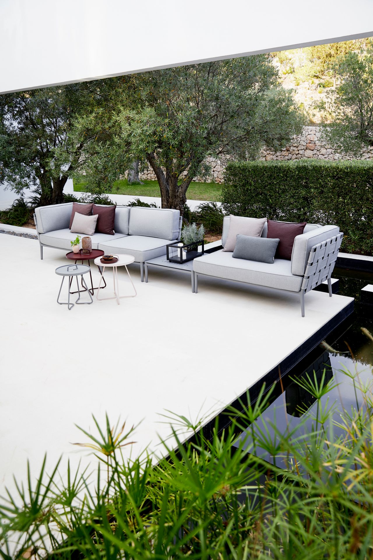 Helles Conic AirTouch Outdoor Modul von Cane-Line mit grauen Kissen und Gartenmöbeln.