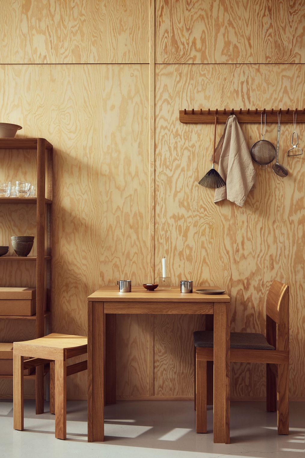 Esszimmer mit Form & Refine Sonder Stuhl mit Polster, Holztisch, Regal und Küchenutensilien an der Wand.