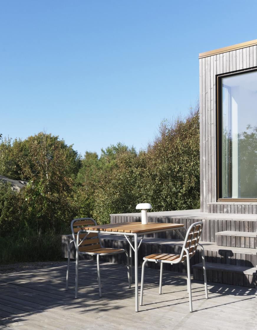 Nahaufnahme von zwei Vig Chair Wood Stühlen von Normann Copenhagen und einem Holztisch im Freien.