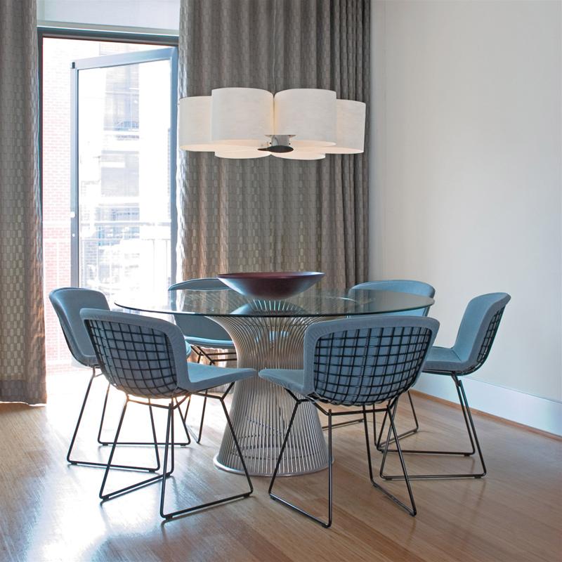Esszimmer mit rundem Glastisch und sechs Bertoia Stühlen mit hellblauer Vollpolsterung von Knoll International.