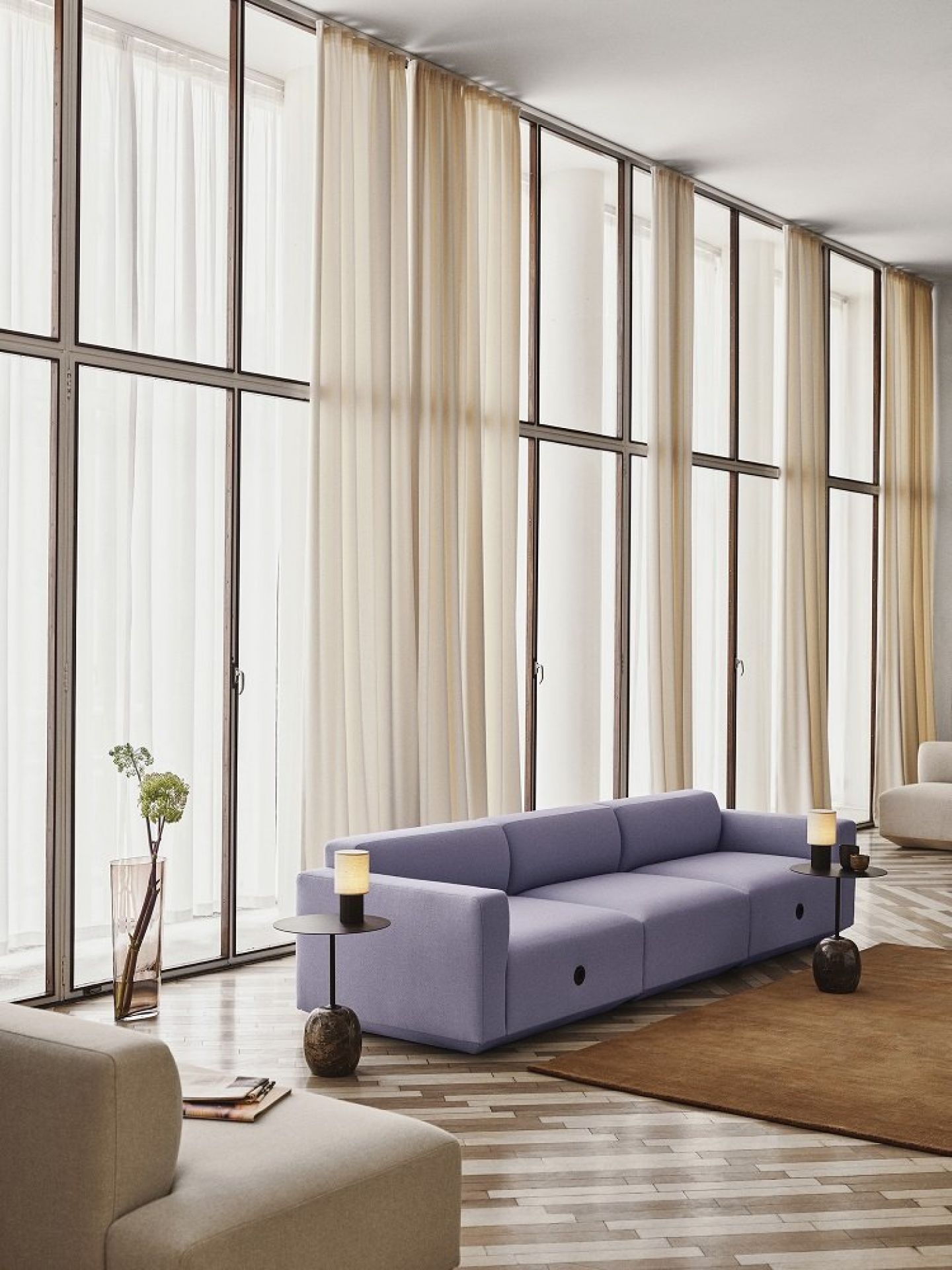 Nahaufnahme der AndTradition Manhattan SC52 Akkuleuchte auf einem Beistelltisch neben einem lila Sofa.