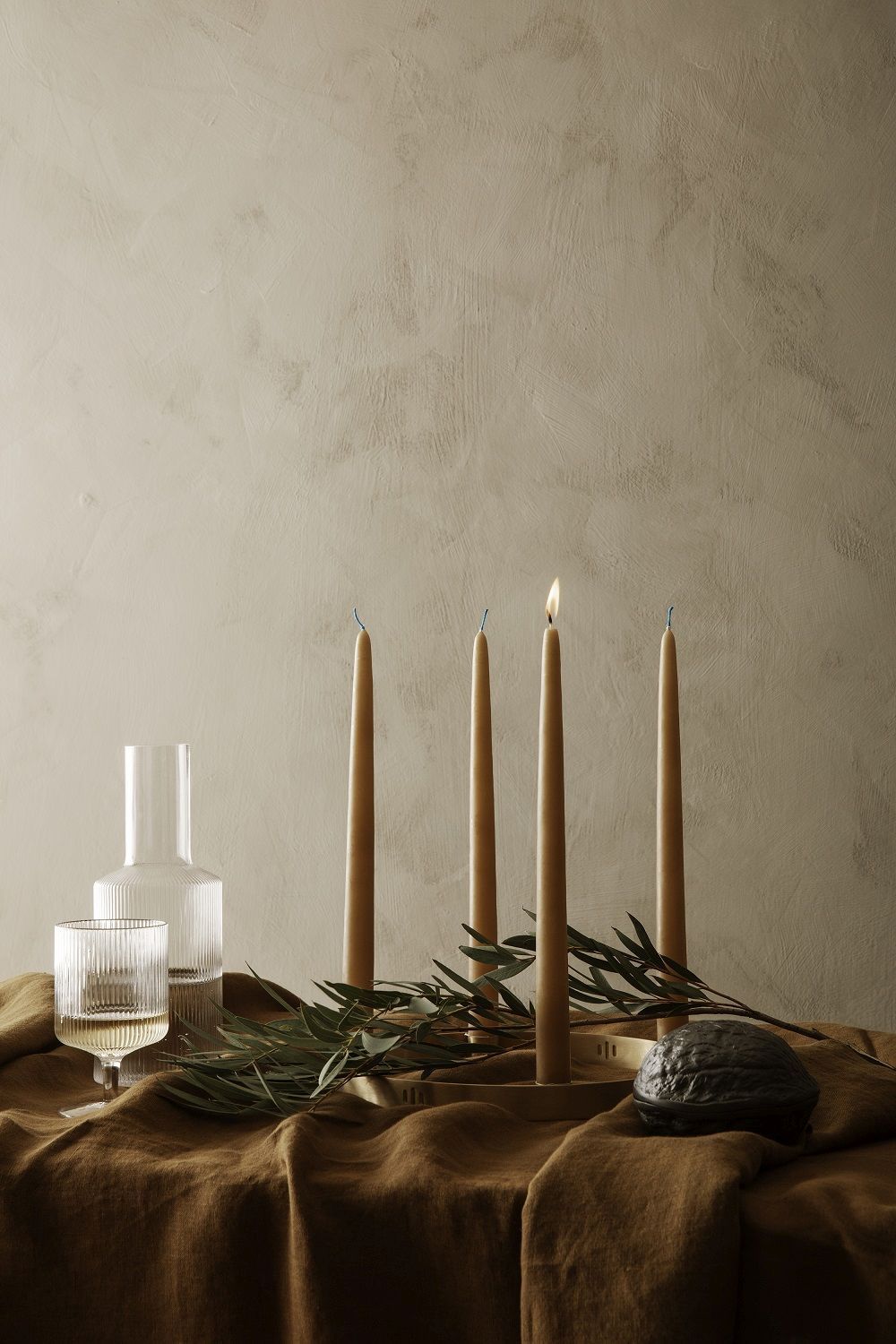 Stillleben mit Kerzen, Glas, Zweigen und Ferm Living Forest Nut Box in Schwarz.