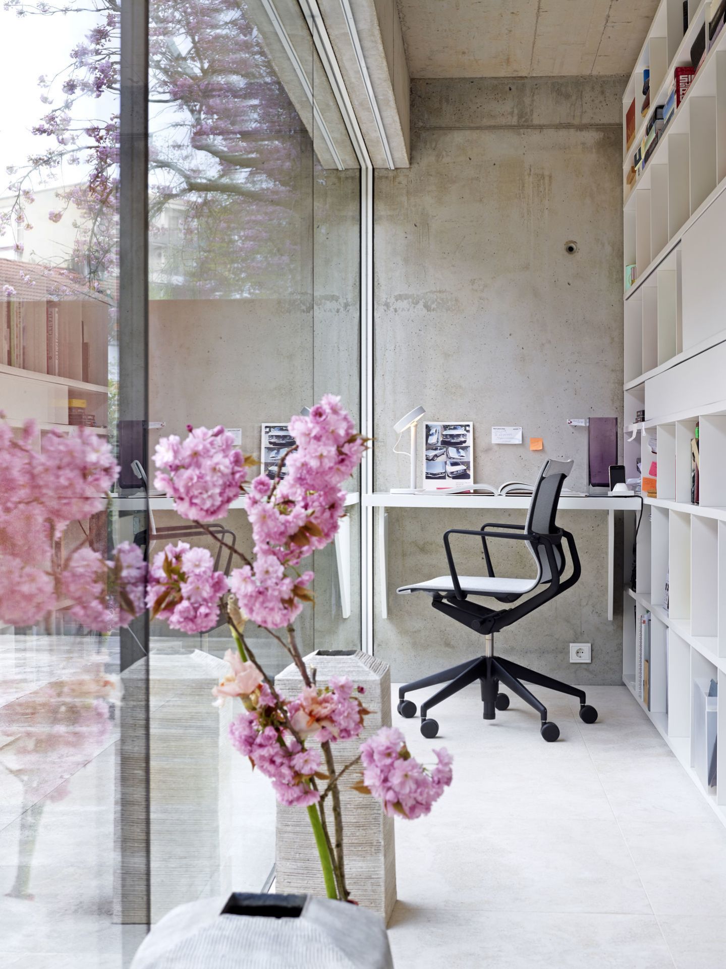 Moderner Physix Bürostuhl von Vitra in minimalistischem Büro mit Betonwand und Bücherregal.
