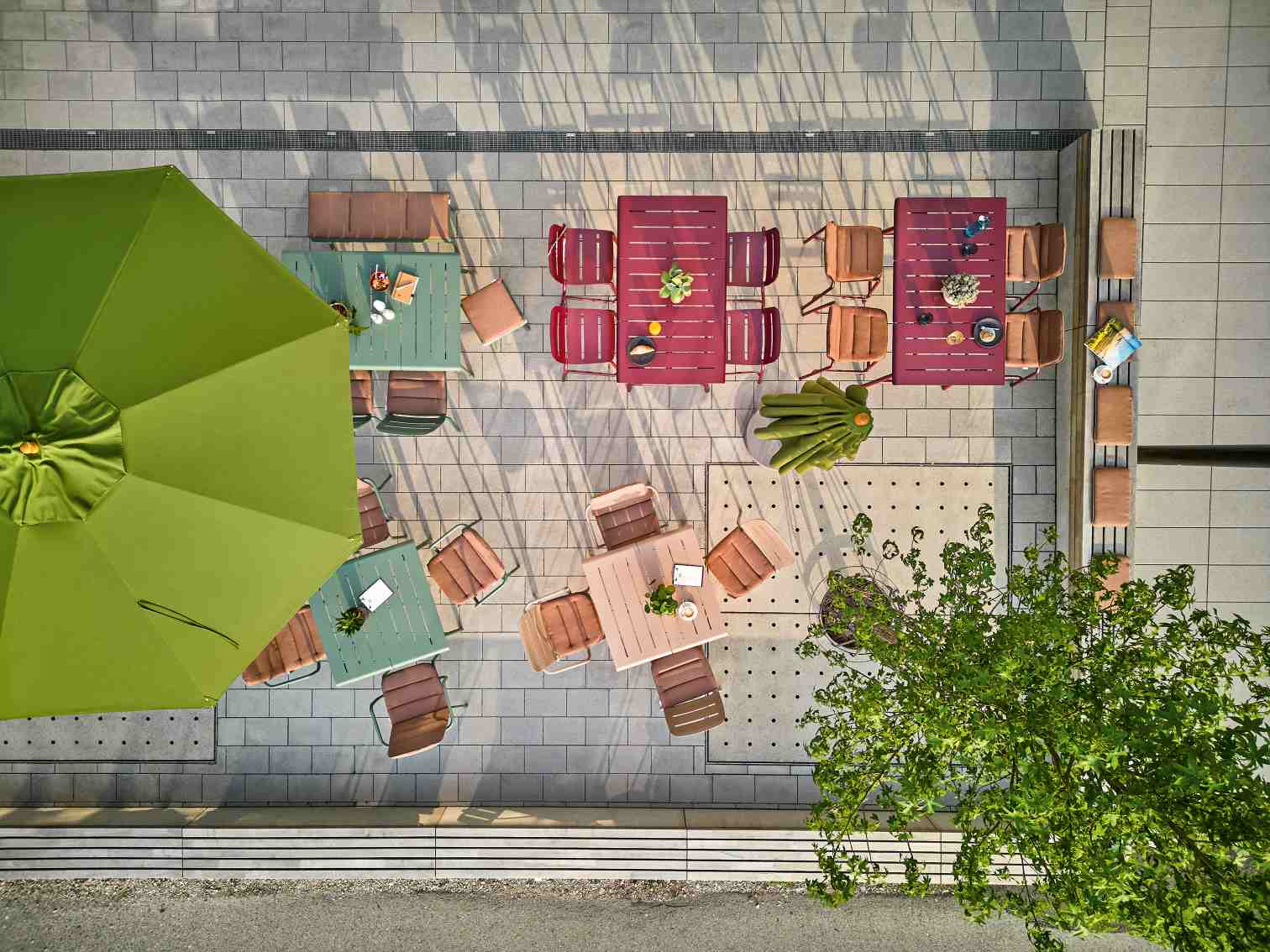 Vapio Stuhl Outdoor Weishäupl: Luftaufnahme von mehreren farbigen Gartentischen und Stühlen auf einer Terrasse.