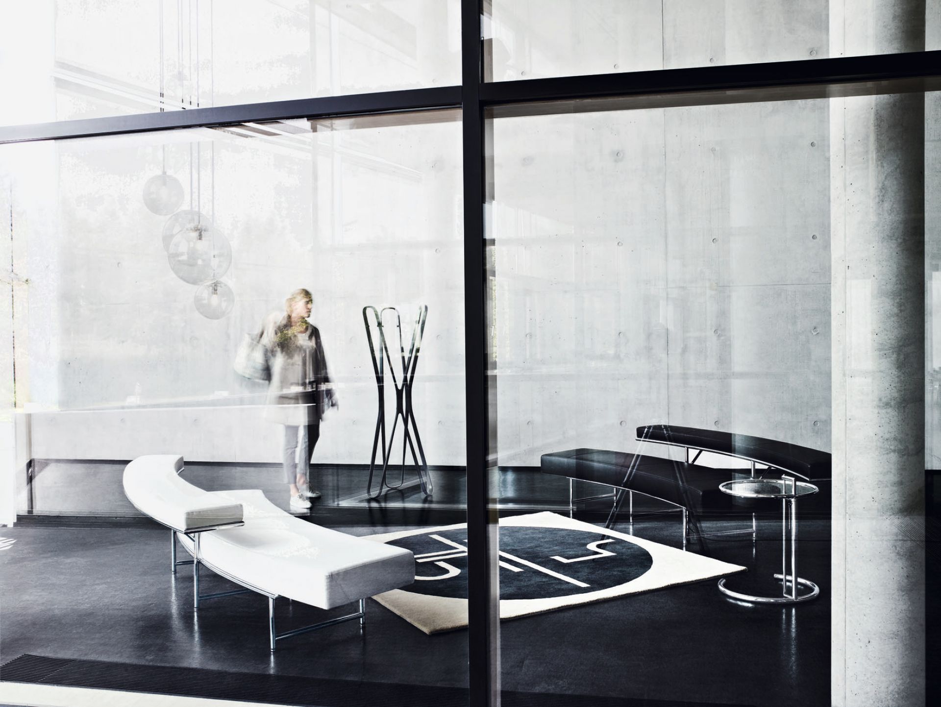 Moderner Ausstellungsraum mit ClassiCon Adjustable Table E1027 Beistelltisch, Designermöbeln und minimalistischem Interieur.