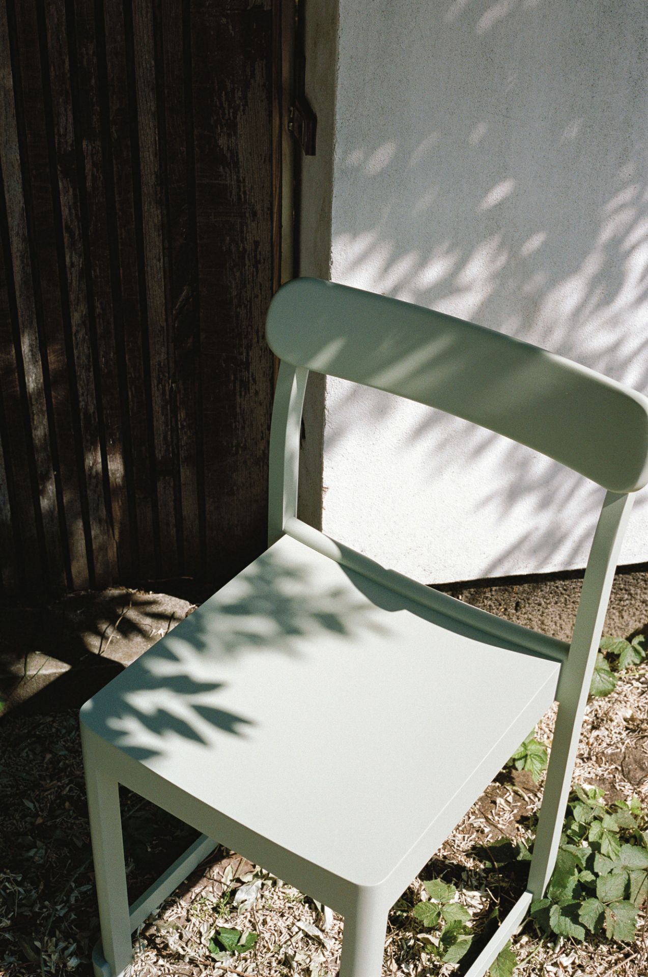 Heller Atelier Chair Stuhl von Artek im Außenbereich, modernes Design mit Schattenmuster.