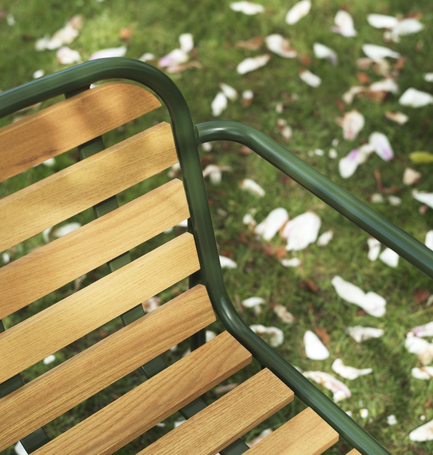 Detailaufnahme des Vig Armchair Wood Armlehnstuhls von Normann Copenhagen, ideal für den Outdoor-Bereich, mit Holzlatten und grünen Armlehnen.