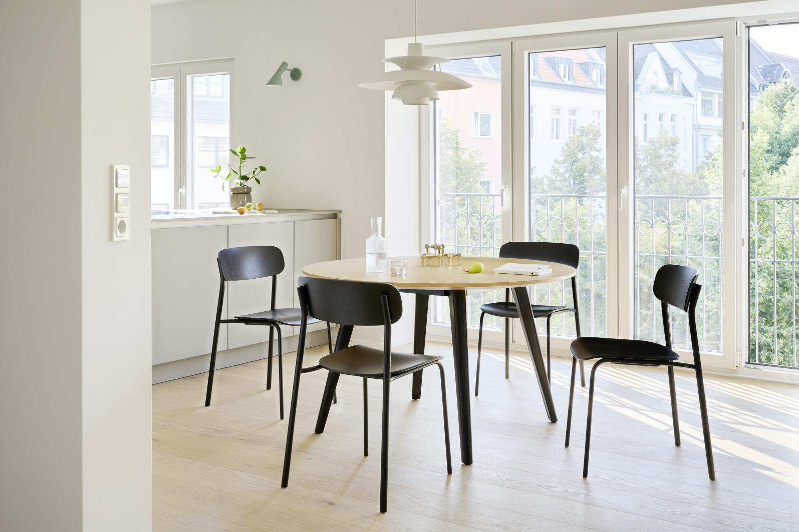 Esszimmer mit vier schwarzen Stahlrohrstühlen S 243 von Thonet um einen runden Holztisch.