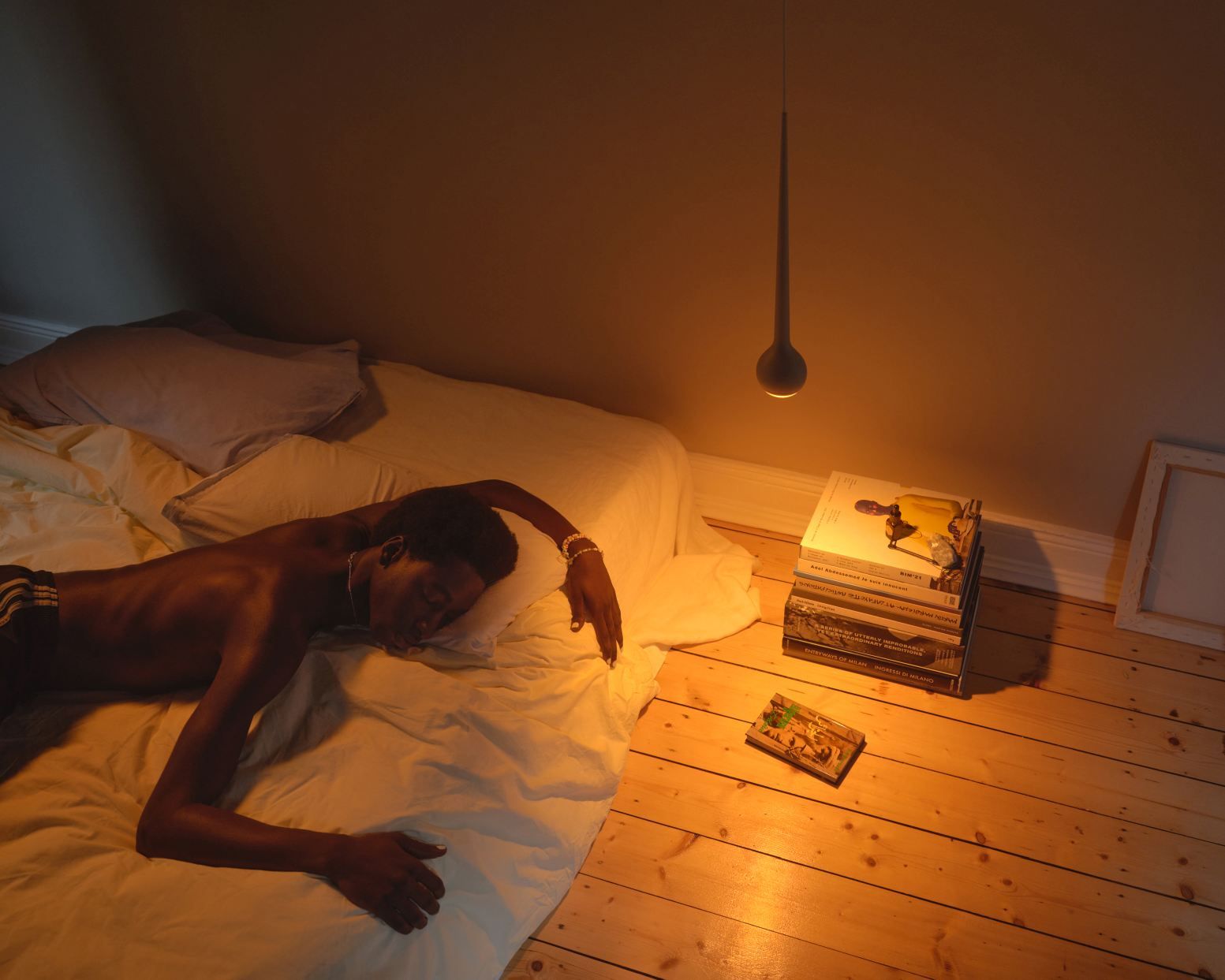 Mann schläft unter der grauen Falling Sun Pendelleuchte. Moderne Hängelampe für Schlafzimmer und Wohnzimmer.