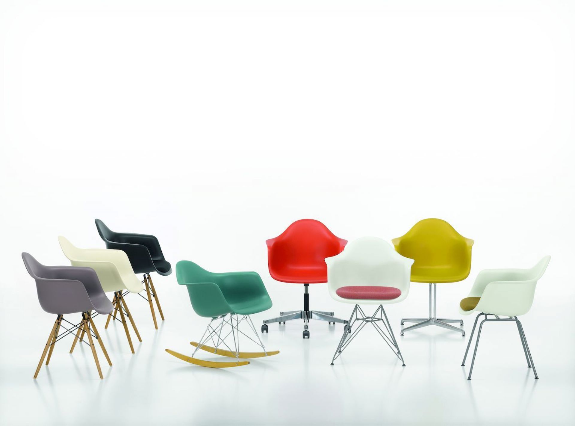 Gruppe von Eames Plastic Arm Chairs PACC mit Sitzpolster von Vitra in verschiedenen Farben und Ausführungen.