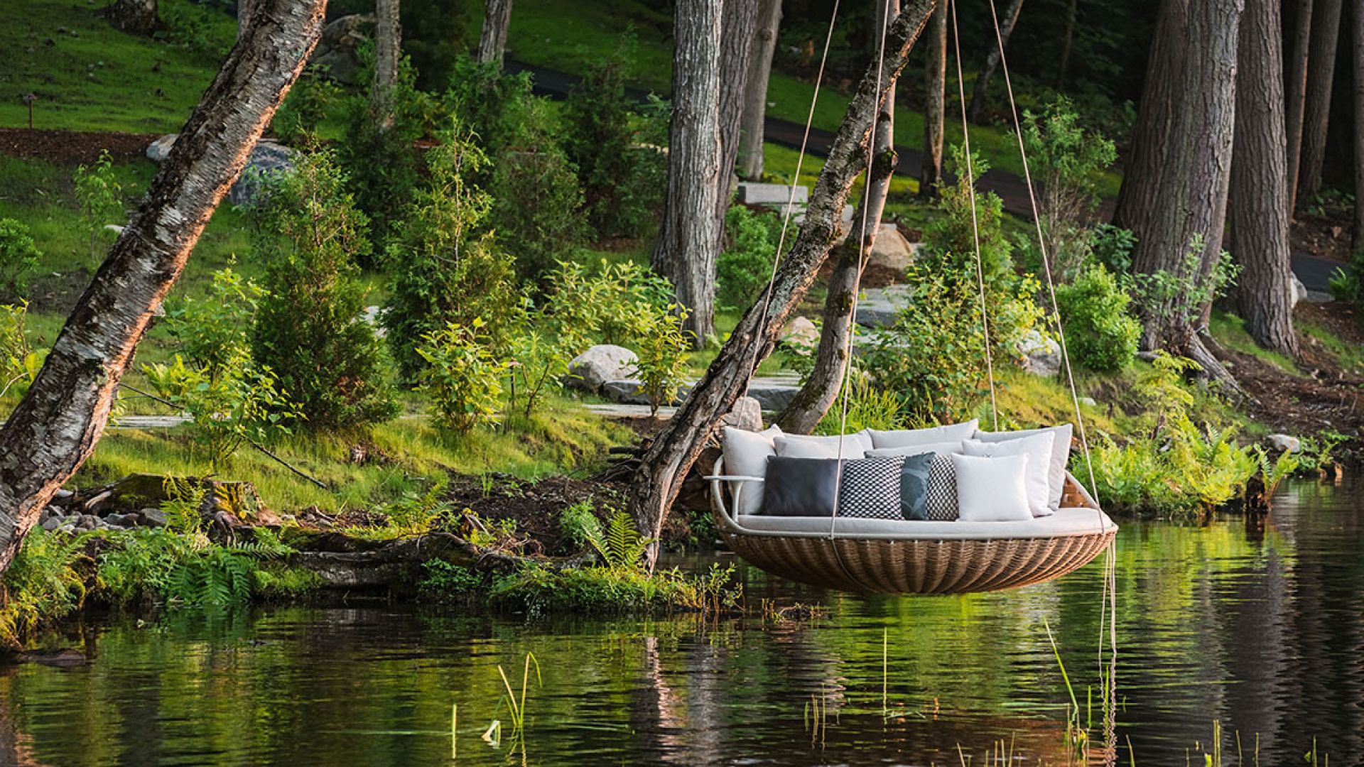 Rückenkissen auf Swingrest Hängeliege von Dedon über Wasser, umgeben von Bäumen. Outdoor Möbel für Garten und Terrasse.