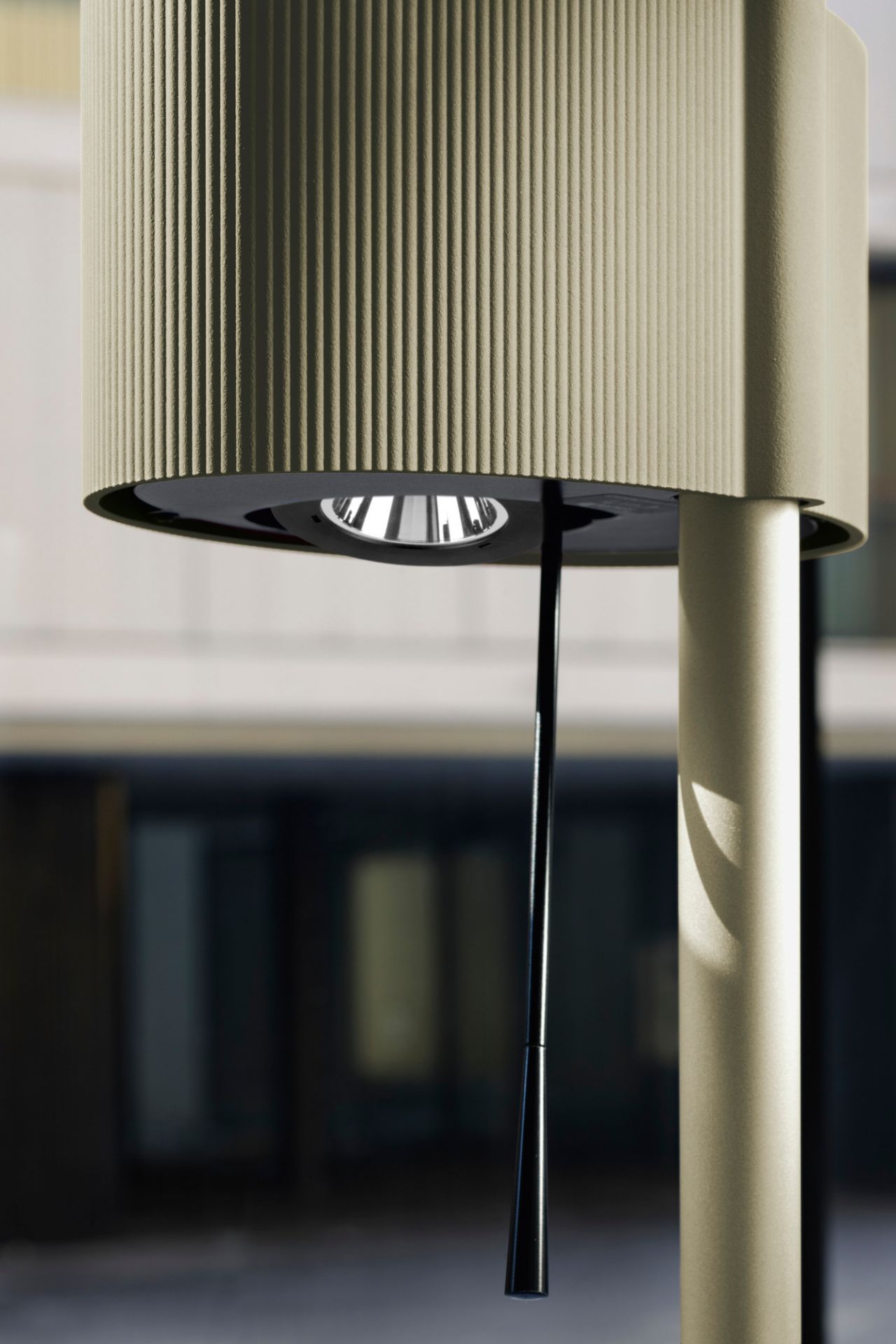 Detailaufnahme der Belux Diogenes LED Stehleuchte mit geripptem Lampenschirm und schwarzem Zugschalter vor Gebäude.
