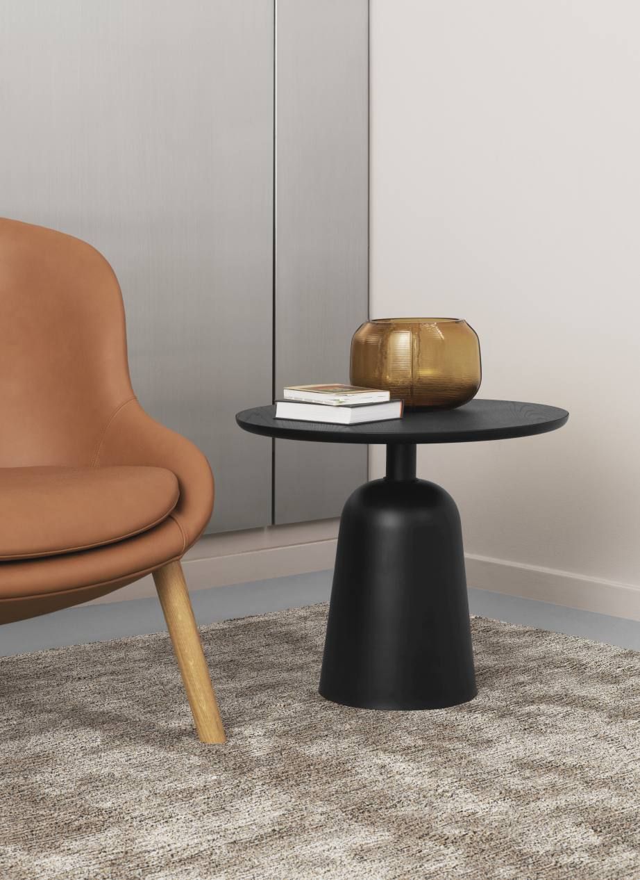 Normann Copenhagen Turn Table Tisch in Schwarz mit Vase und Büchern auf einem Teppich.