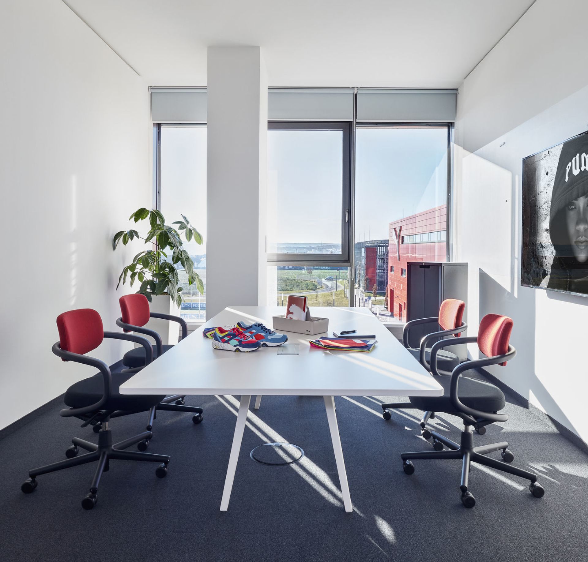 Konferenzraum mit vier Allstar Bürodrehstühlen von Vitra in Schwarz und Rot am weißen Tisch.