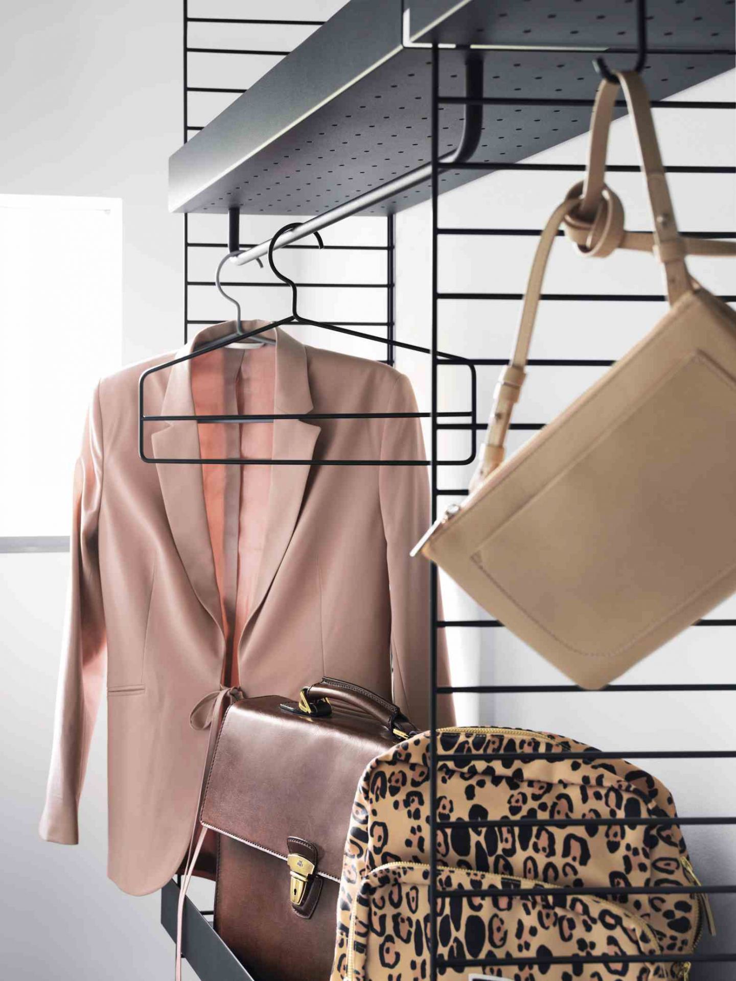Schwarzes String Regalsystem mit Kleidung: Blazer, Aktentasche und Tasche. Vielseitige Wandregale für Schlafzimmer und mehr.