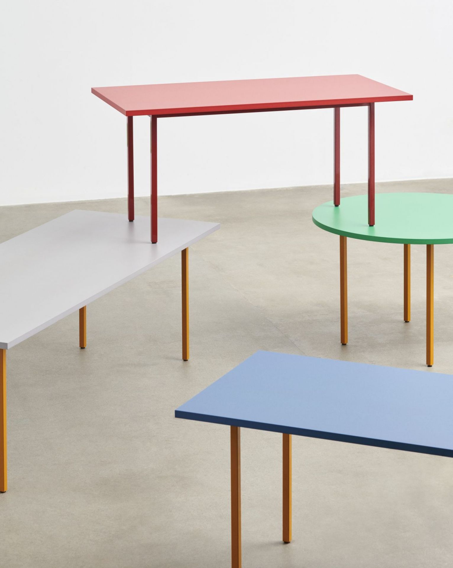 Mehrere moderne Hay Tische in verschiedenen Formen und Farben, darunter ein blauer Two Colour Table mit ockerfarbenen Beinen.