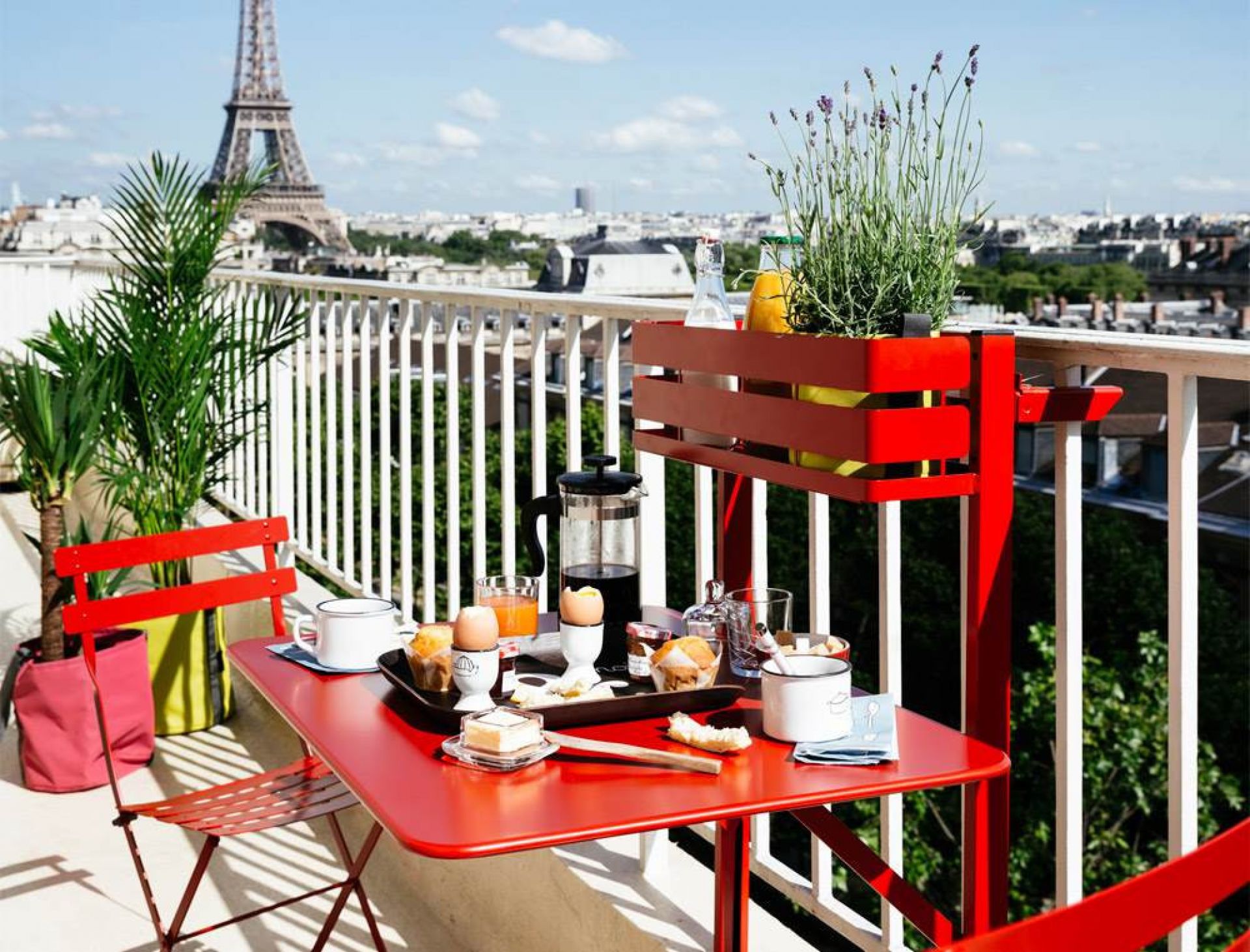 Roter Bistro Balkontisch von Fermob mit Frühstück auf einem Pariser Balkon mit Eiffelturm.