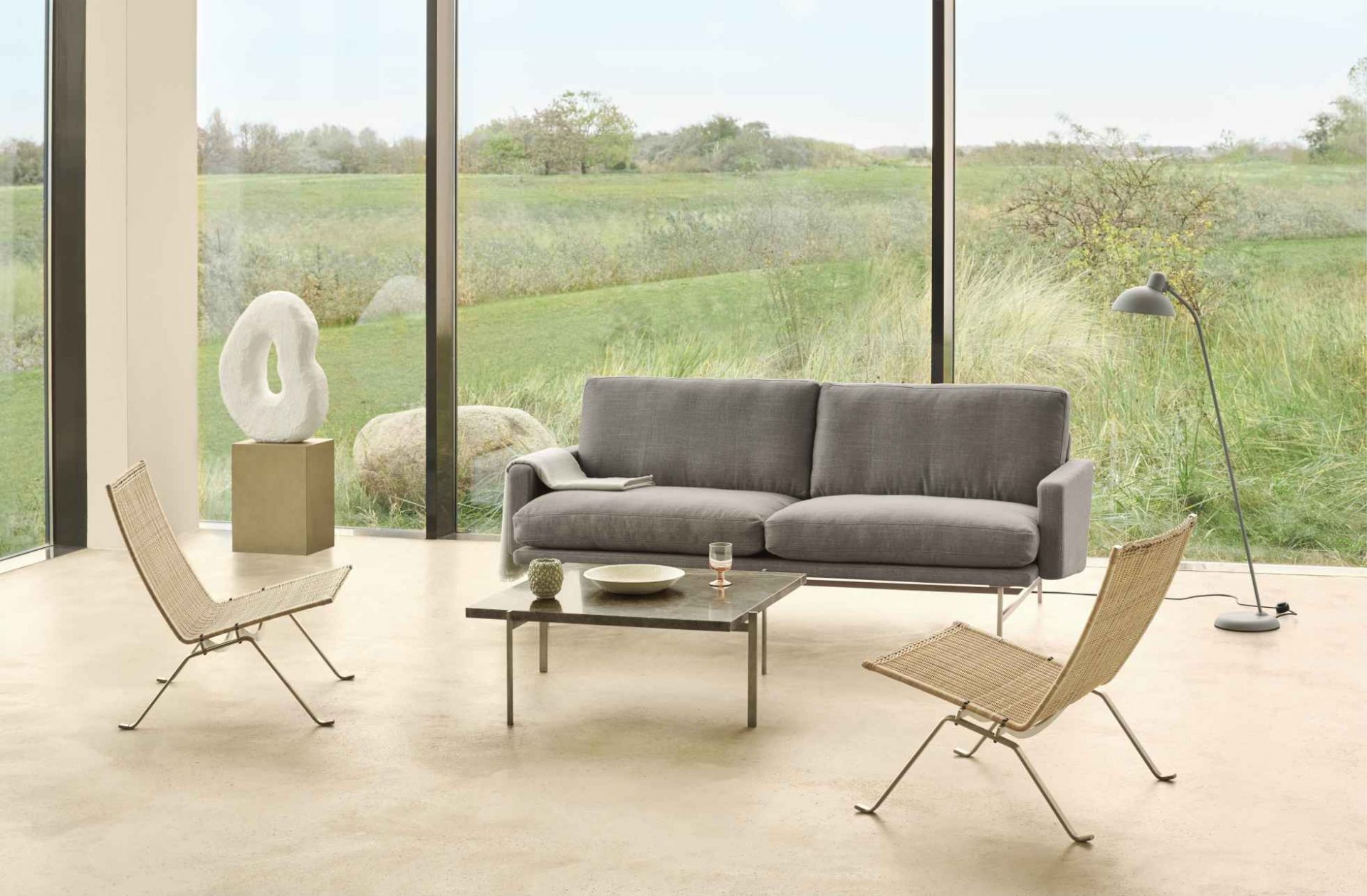 PK 61 Couchtisch von Fritz Hansen im modernen Wohnzimmer mit Sofa und Rattan-Stühlen.