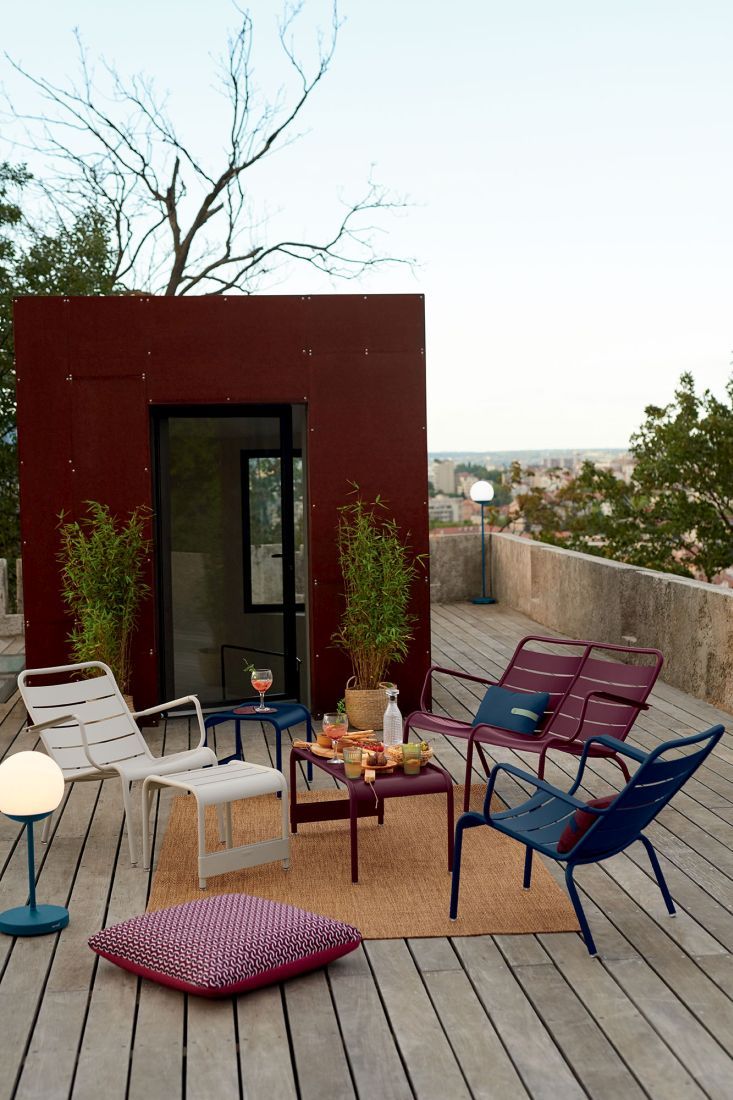 Luxembourg Lounge Sessel von Fermob auf einer Terrasse mit Outdoor-Möbeln und Blick auf die Stadt.