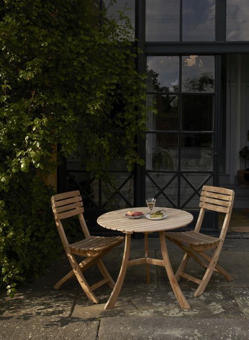 Vendia Klappstuhl von Skagerak by Fritz Hansen mit passendem Gartentisch aus Teakholz im Außenbereich.