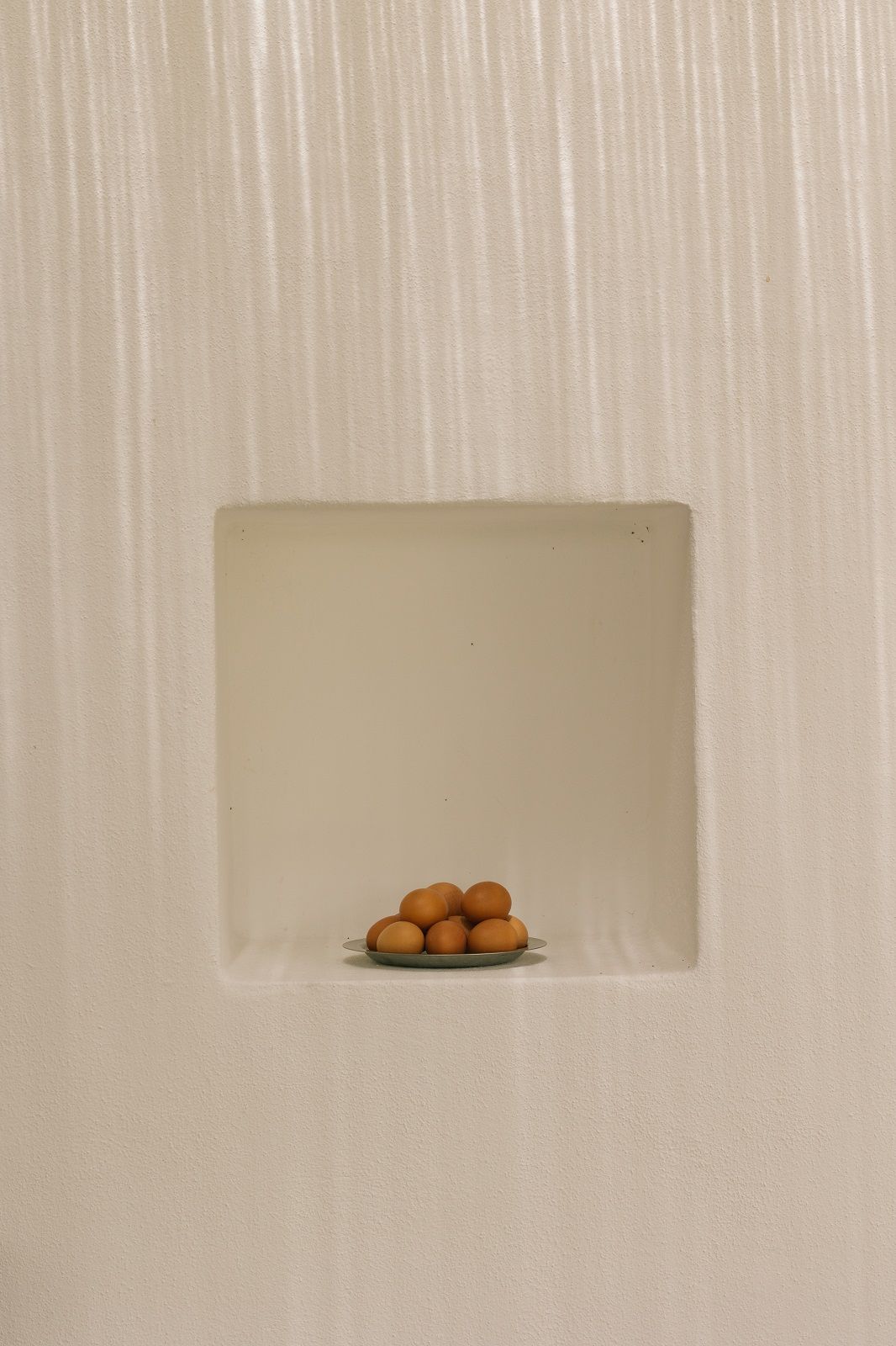Tumbled Plate von Ferm Living: Silberner Camping Teller mit braunen Eiern in einer Nische.