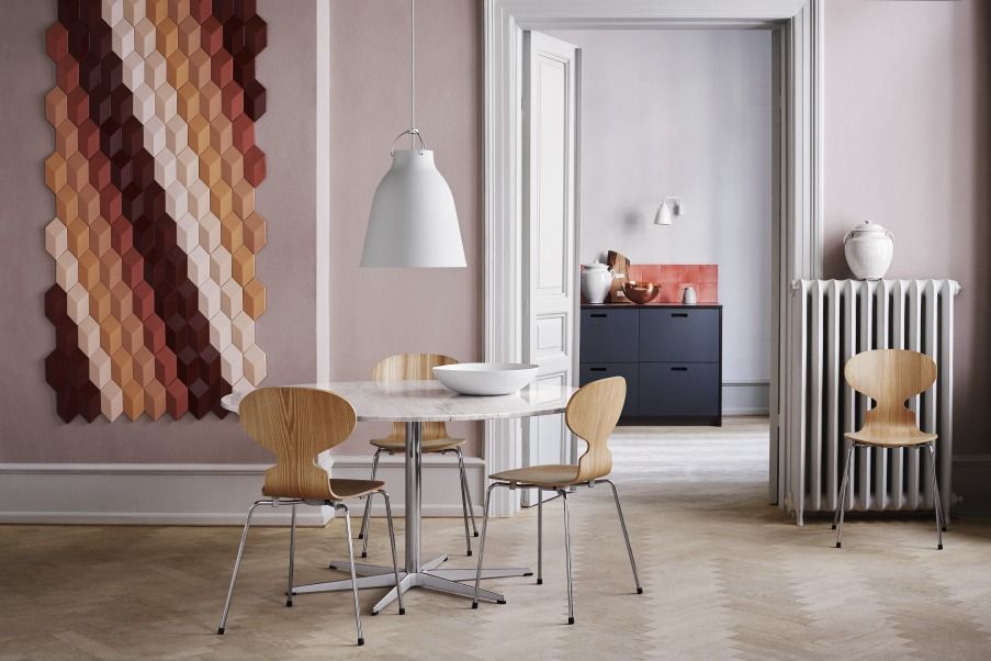 Esszimmer mit Fritz Hansen Caravaggio Pendelleuchte in Weiß über einem runden Marmortisch mit Holzstühlen.