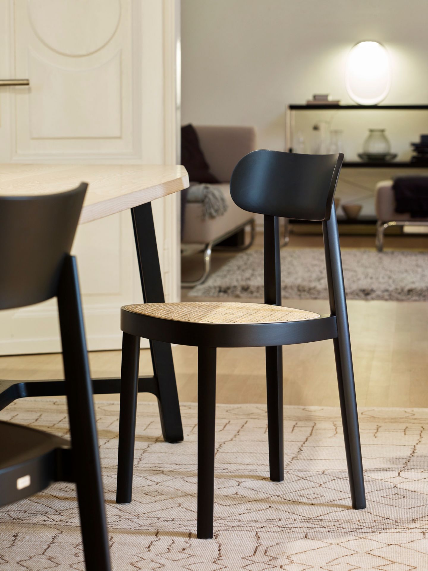 Schwarzer Holzstuhl mit Wiener Geflecht Sitzfläche, Modell 118 von Thonet, im modernen Wohnraum.