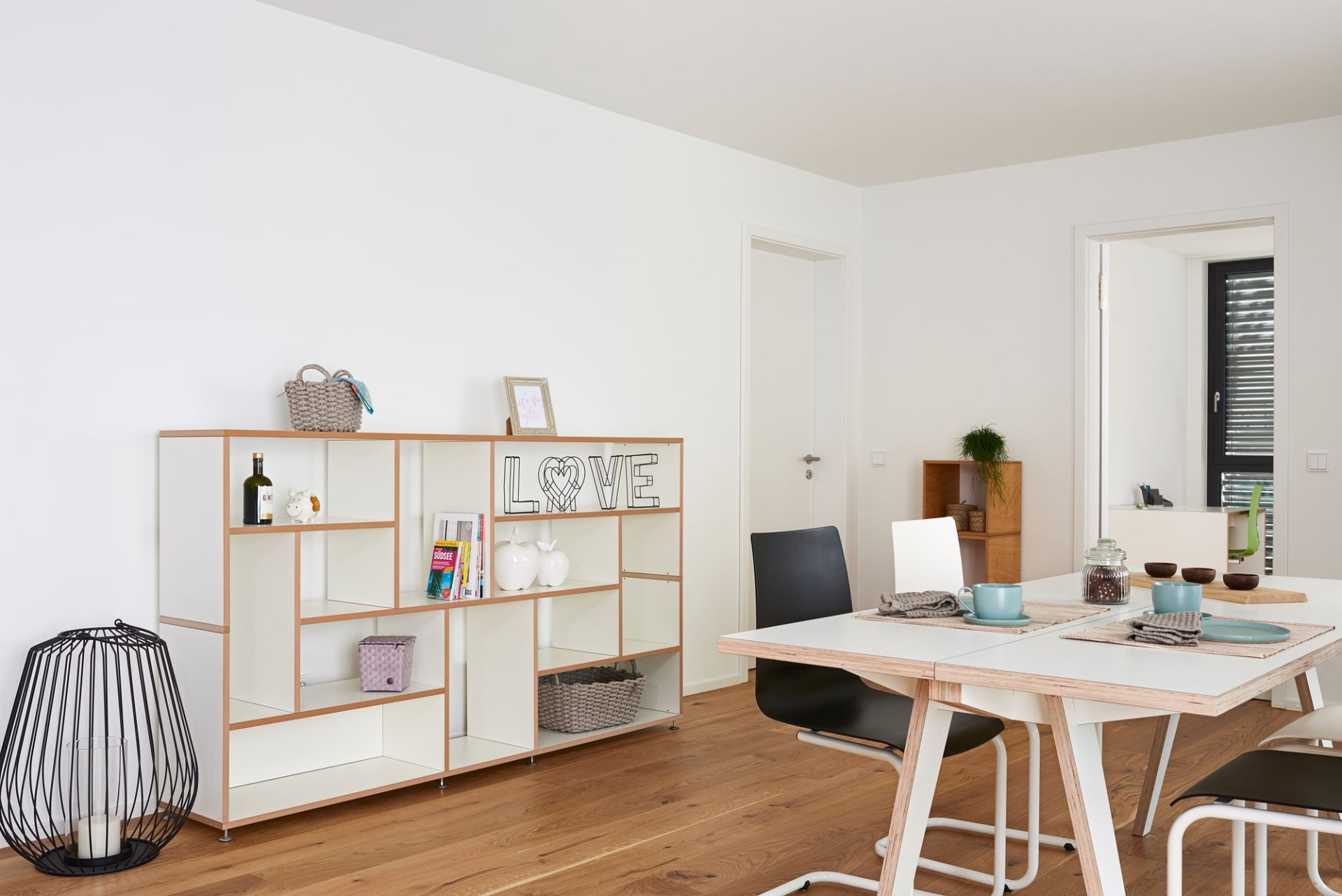 Helles Wohnzimmer mit Tojo Hanibal Sideboard, Tisch und Stühlen auf Holzboden.