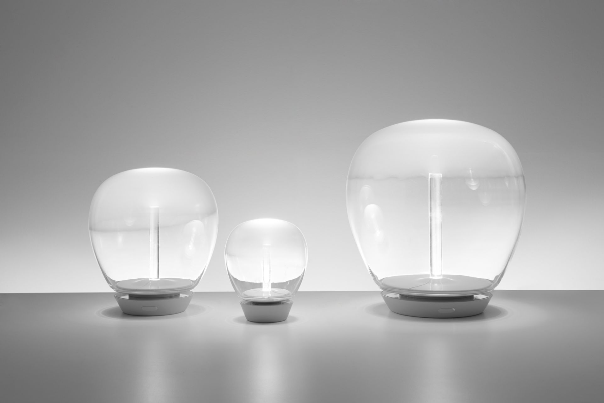 Drei Artemide Empatia Tischleuchten in verschiedenen Größen mit transparentem Glasdiffusor.