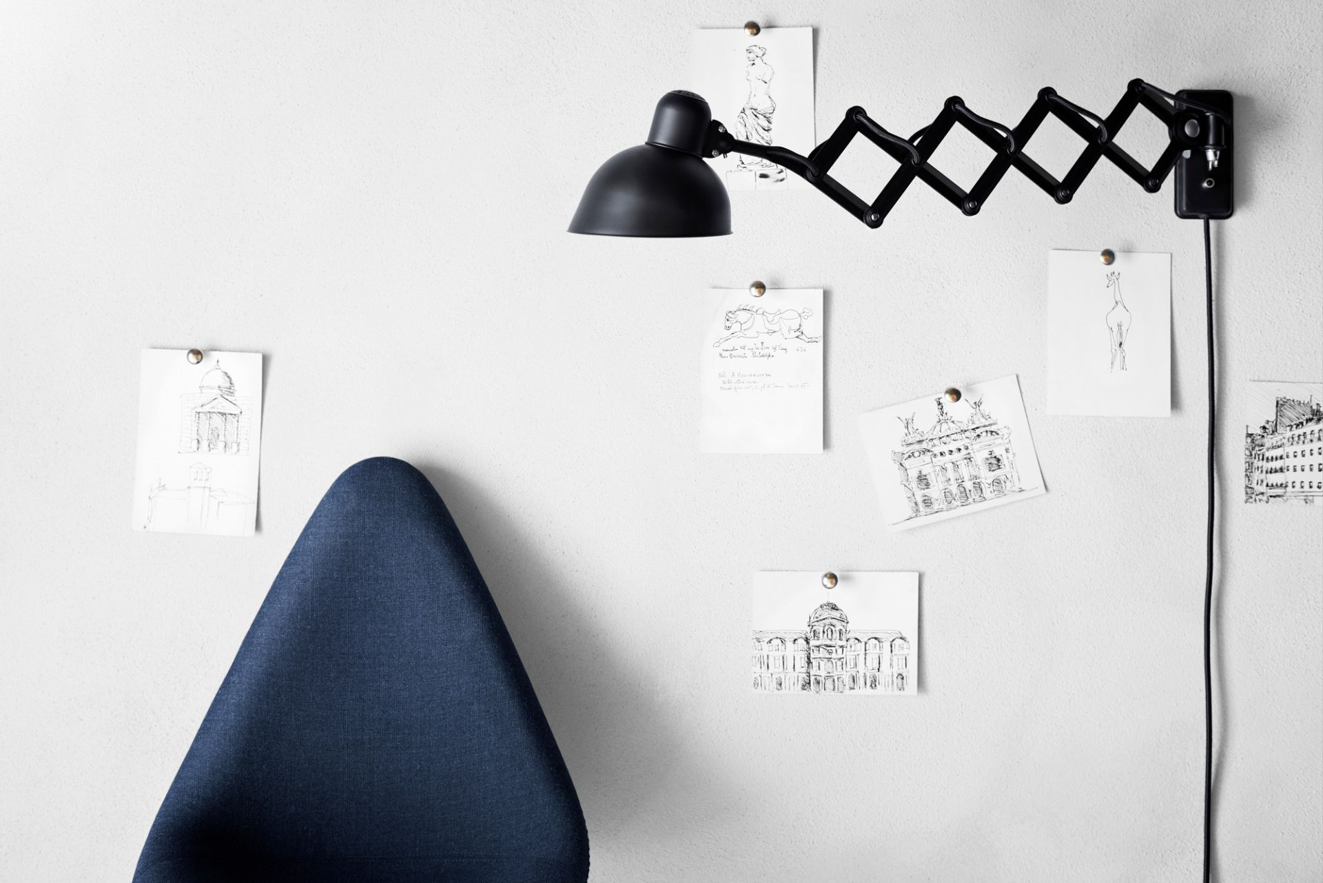Schwarze KAISER idell Scherenleuchte 6718 von Fritz Hansen an weißer Wand mit Zeichnungen. Designklassiker.
