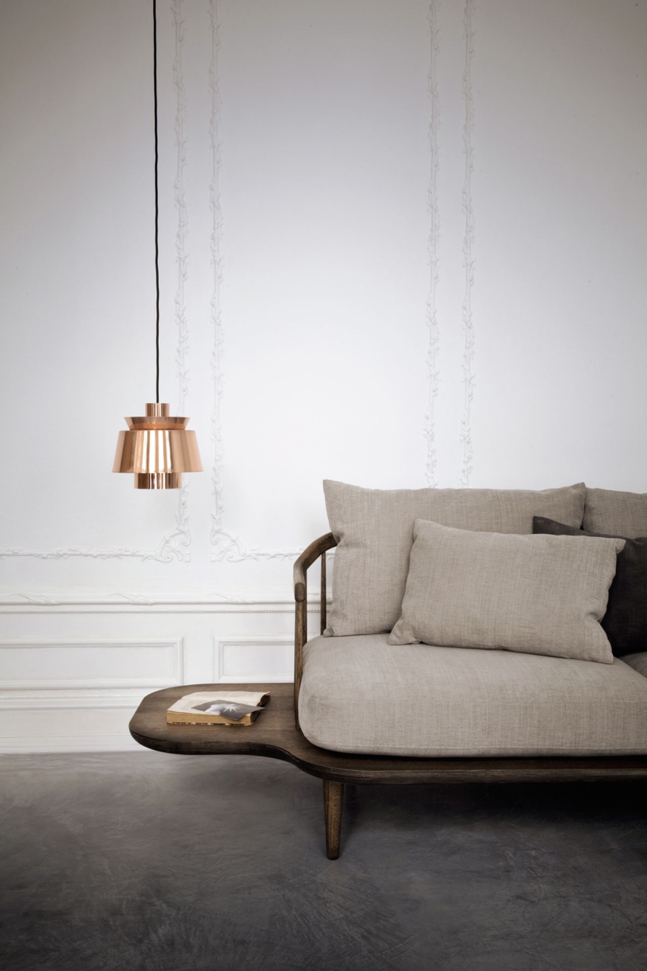Nahaufnahme der Utzon Pendelleuchte von AndTradition in Kupfer über einem stilvollen Sofa.