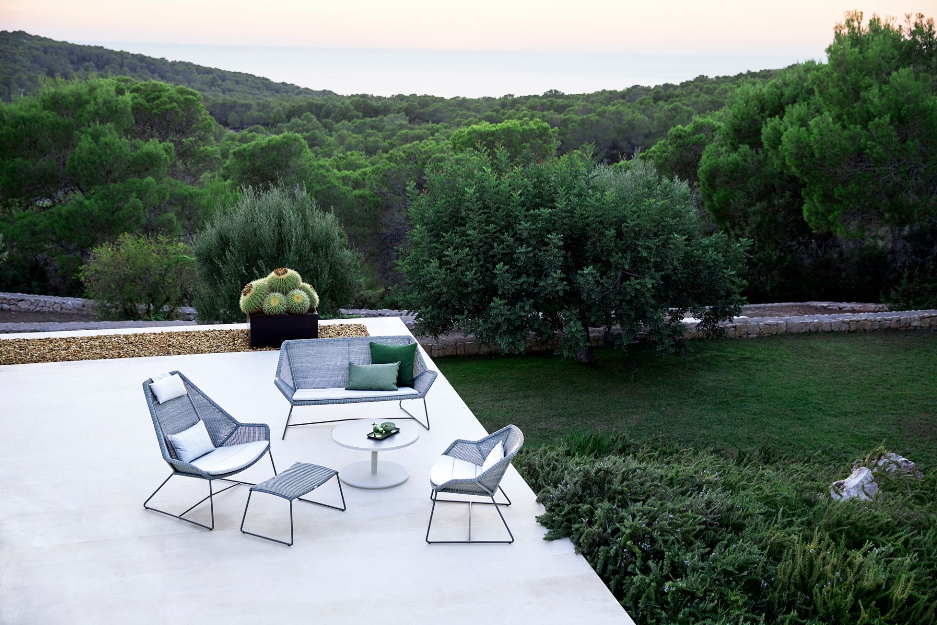 Breeze Cane-Line Outdoor Highbacksessel und Lounge-Möbel auf Terrasse mit Blick in die Natur.