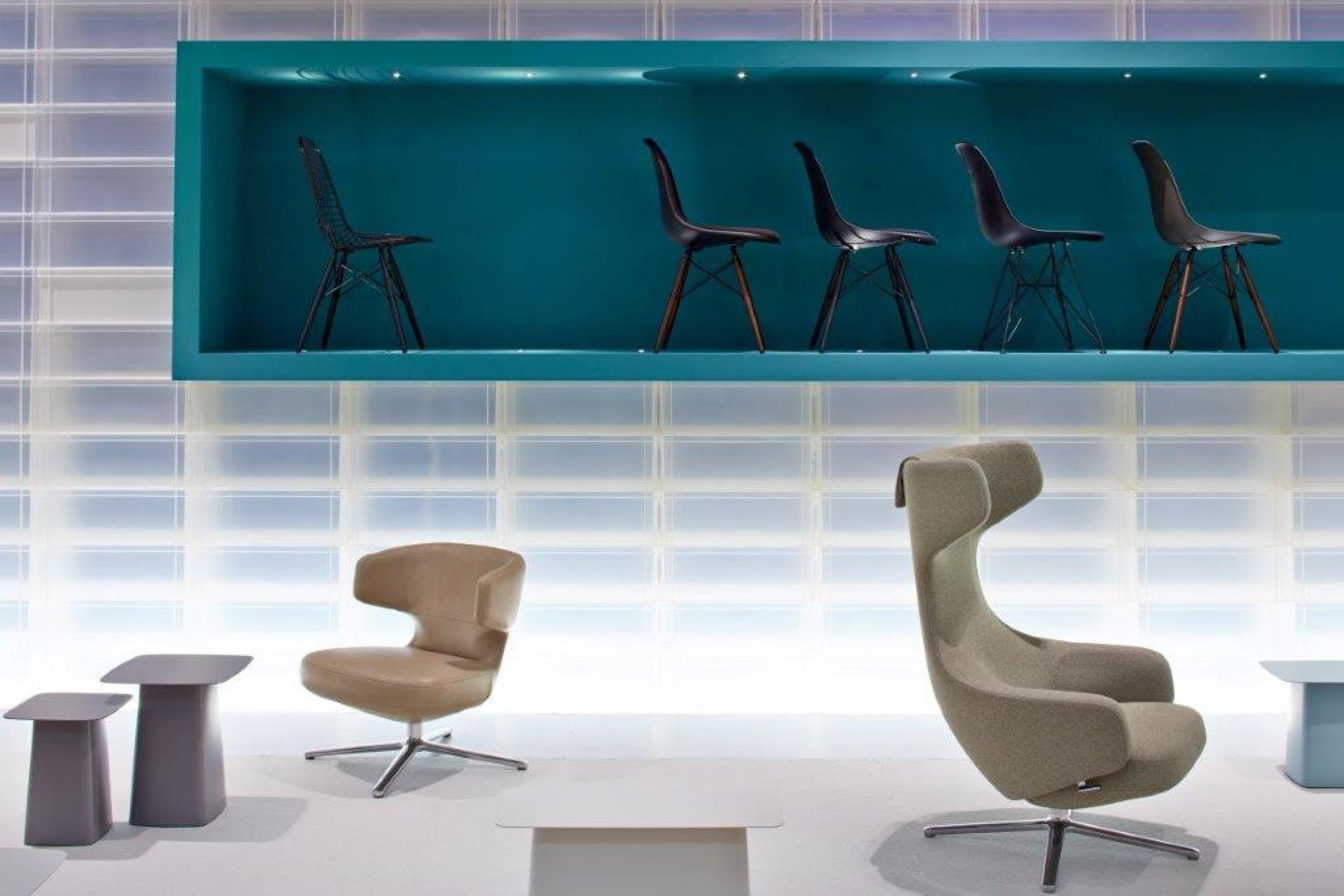 Vitra Petit Repos Sessel in Beige und Grün, mit Design-Stühlen auf einem Regal.