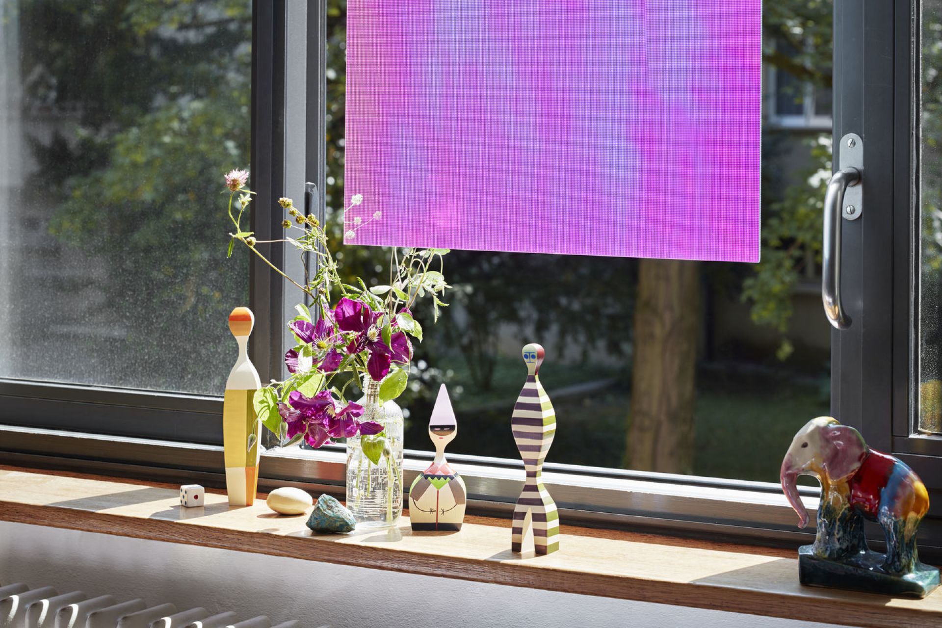 Holzfiguren von Vitra Wooden Dolls auf einer Fensterbank mit Blumen und Dekoration, blickdichtes Rollo.