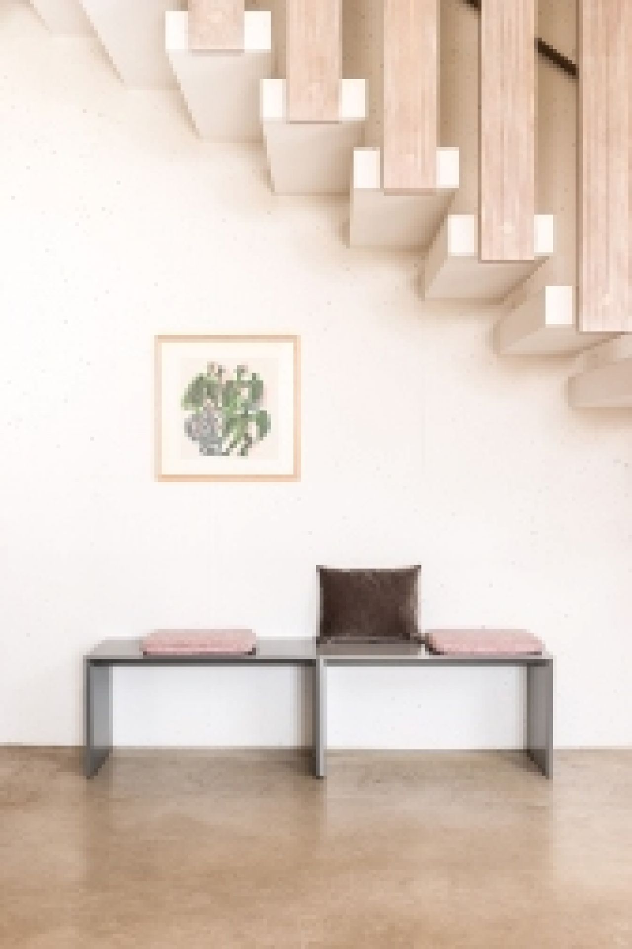 Schönbuch Add On Sitzbank in Grau mit Kissen vor weißer Wand und Treppe.