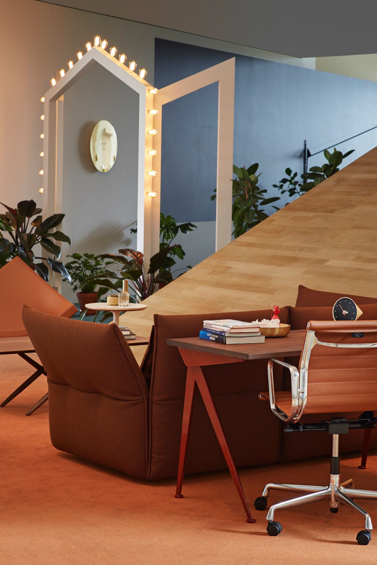 Vitra Compas Direction Schreibtisch mit braunem Bürostuhl und Sofa in einem modernen Büroambiente.