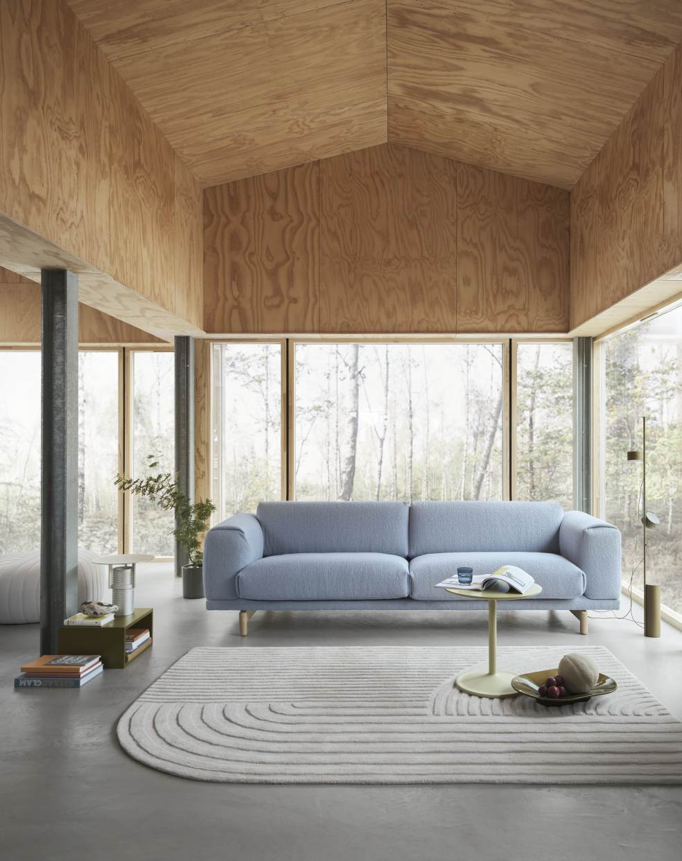 Helles Wohnzimmer mit blauem Rest Sofa von Muuto, minimalistischem Teppich und Holzwänden für gemütliches, modernes Wohnen.