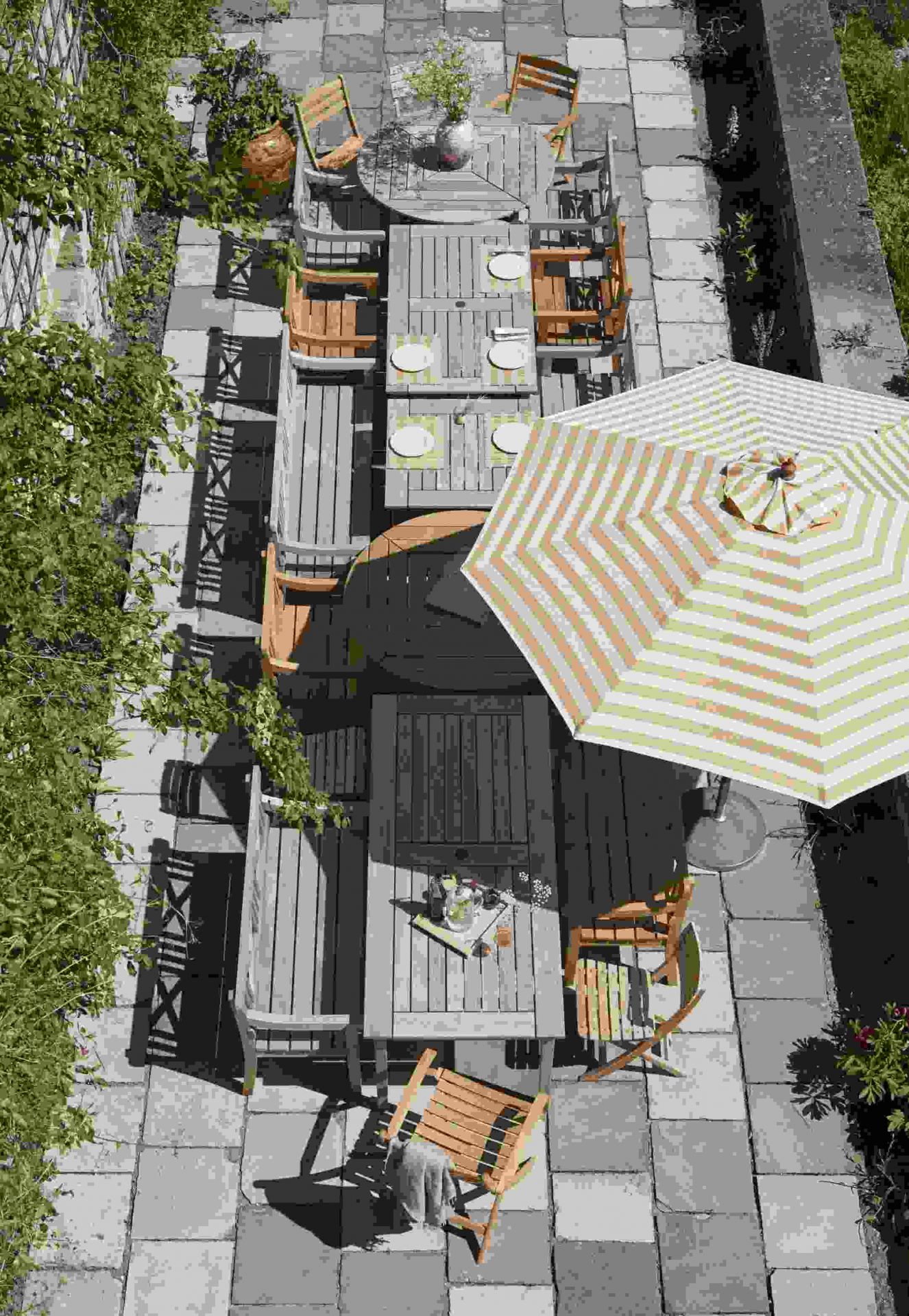 Draufsicht auf eine Gartenterrasse mit mehreren Holztischen und Drachmann Stühlen von Skagerak by Fritz Hansen.