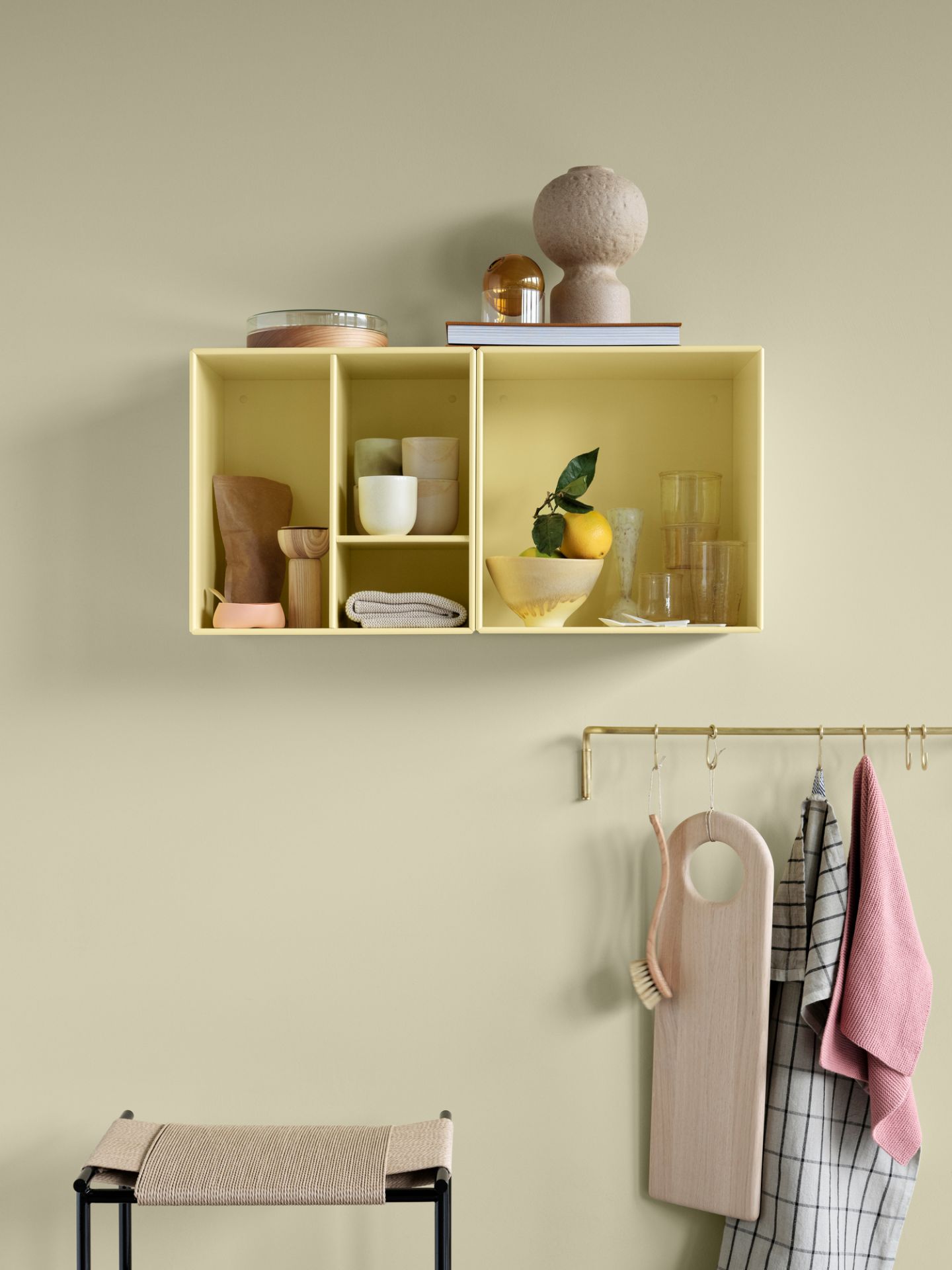 Gelbes Montana Mini Modul mit Regalböden an der Wand, dekoriert mit Geschirr und Deko-Objekten.