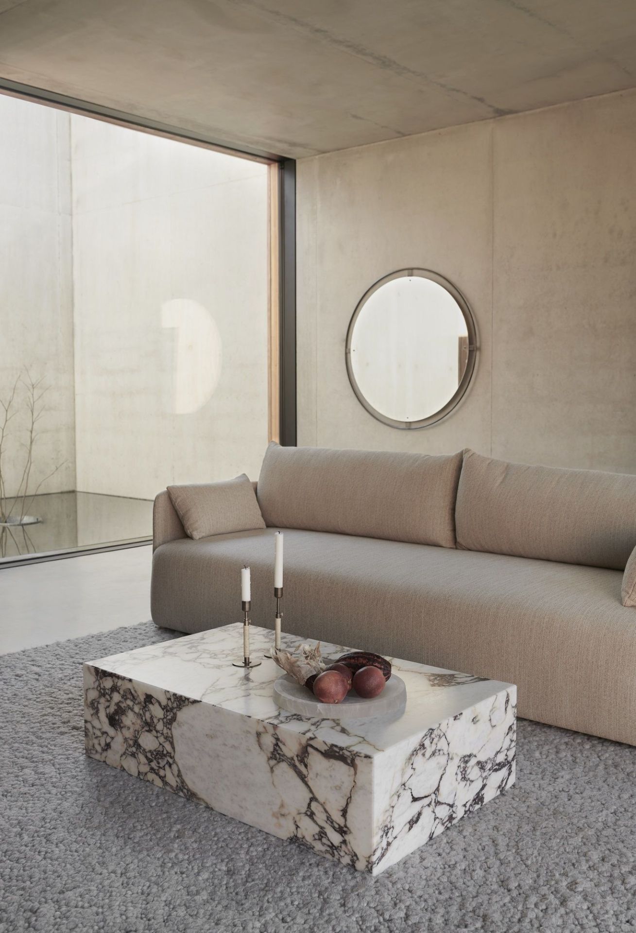 Modernes Wohnzimmer mit Audo Copenhagen Nimbus Spiegel und Marmor-Couchtisch neben beigem Sofa.
