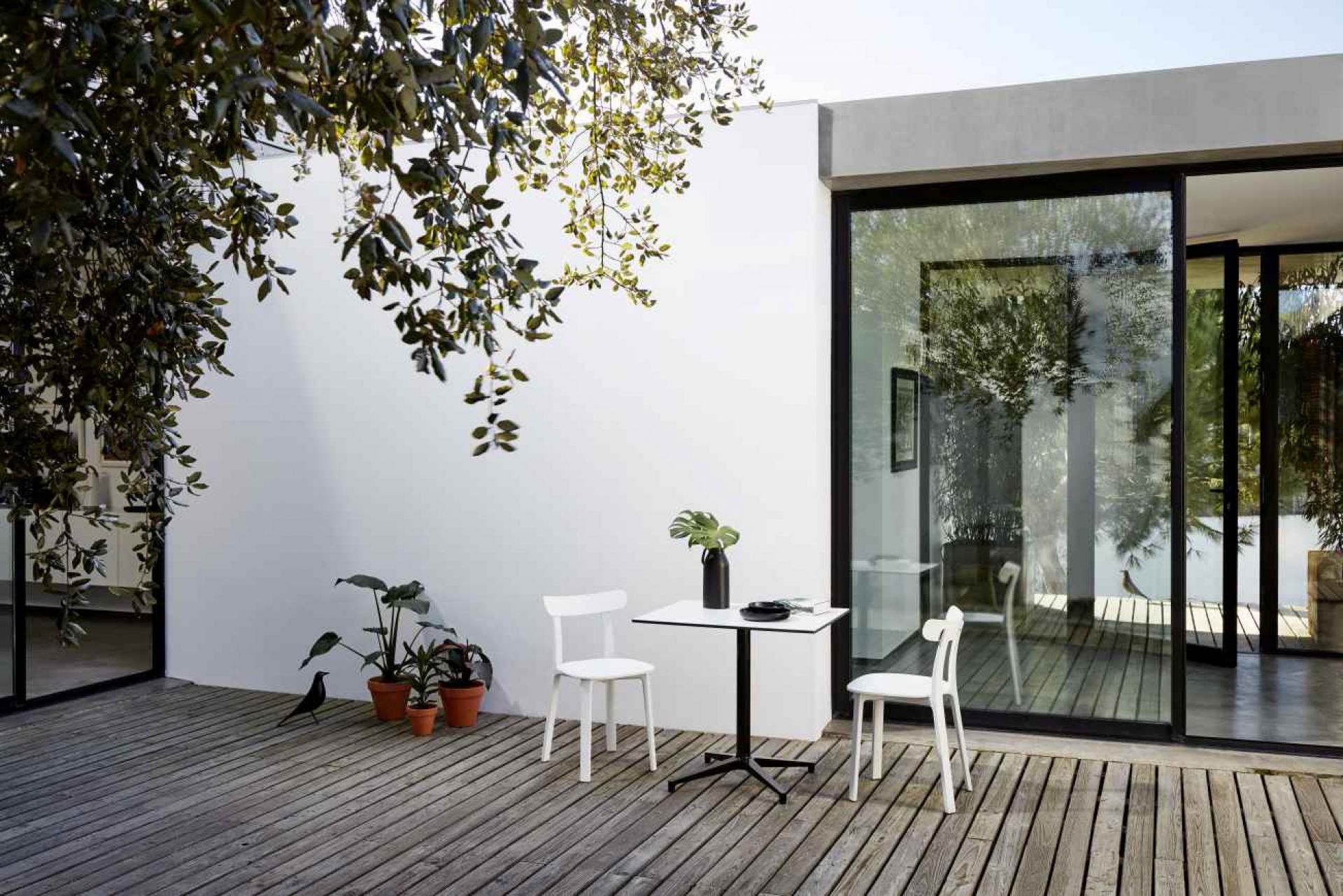 Rechteckiger Vitra Bistro Table Outdoor mit zwei Stühlen auf einer Holzterrasse.