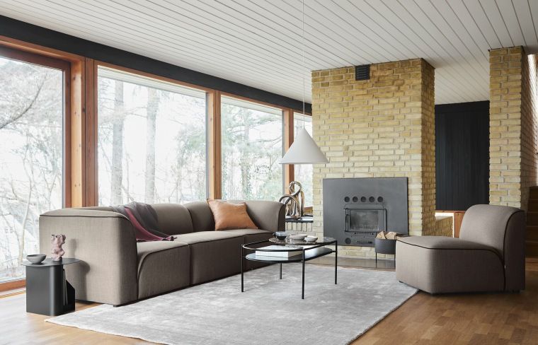 Wohnzimmer mit grauem Woud Teppich, Sofa, Sessel, Kamin und großem Fenster für gemütliches Ambiente.